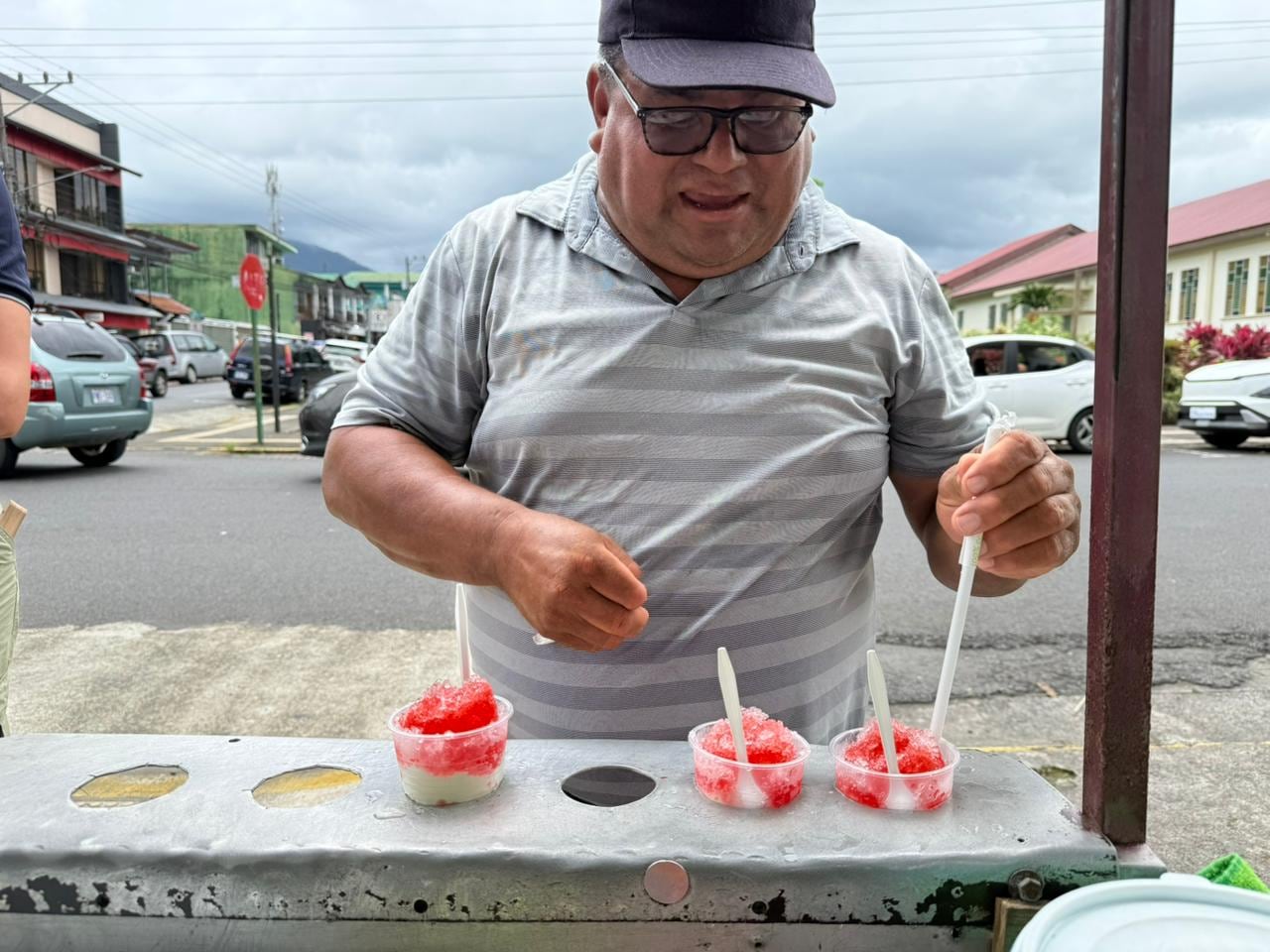 Las personas buscan dónde esconderse cuando cae un aguacero en La Fortuna de San Carlos, pero el nicaragüense, Antonio Padilla Madriz, más bien sonríe y le agradece a Dios porque así venderá más copos