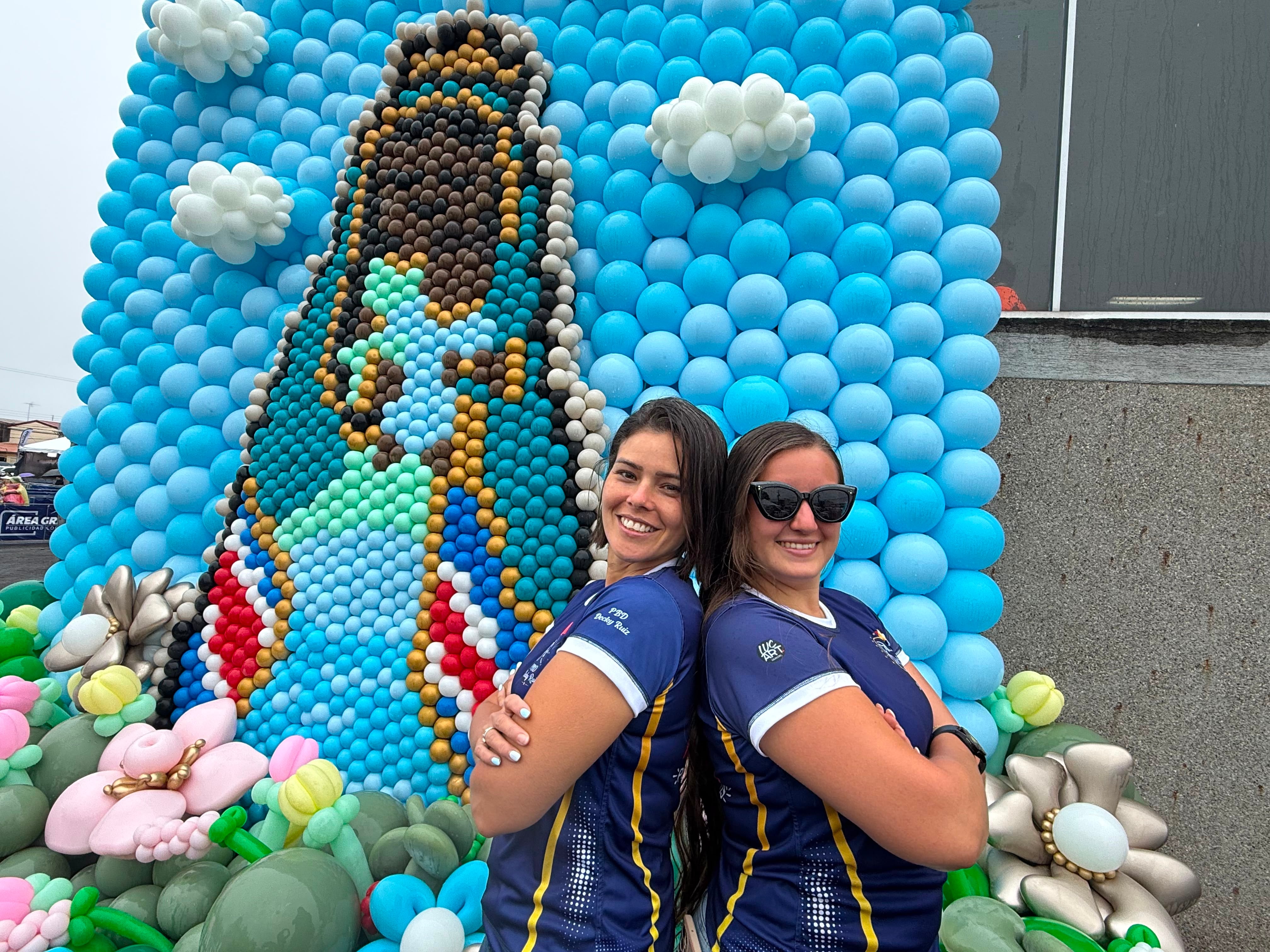 La diseñadora profesional de arte con globos Decky Ruiz, de nacionalidad venezolana y residente en Heredia, presentó una impresionante imagen de la Virgen de los Ángeles de 4,5 metros de altura, hecha con más de 4.500 globos. En la foto le acompaña la tica Priscila Bolaños (derecha) quien también participó.
