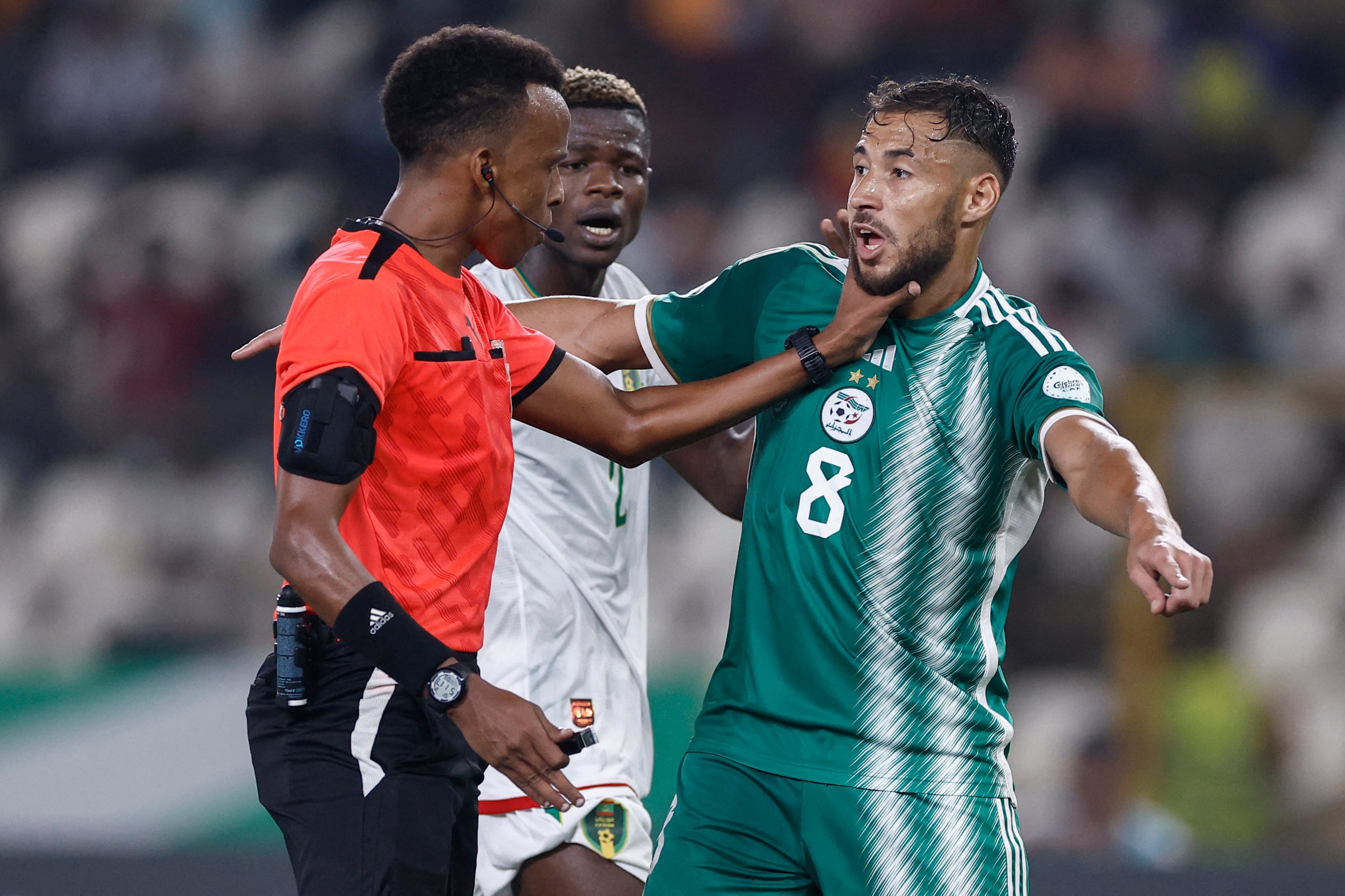 El árbitro de Somalia Omar Abdulkadir Artan pone la mano en el jugador de Argelia Youcef Belaili en la Copa Africana de Naciones 2024. El réferi no pudo entrar a Estados Unidos para el Mundial 2026.