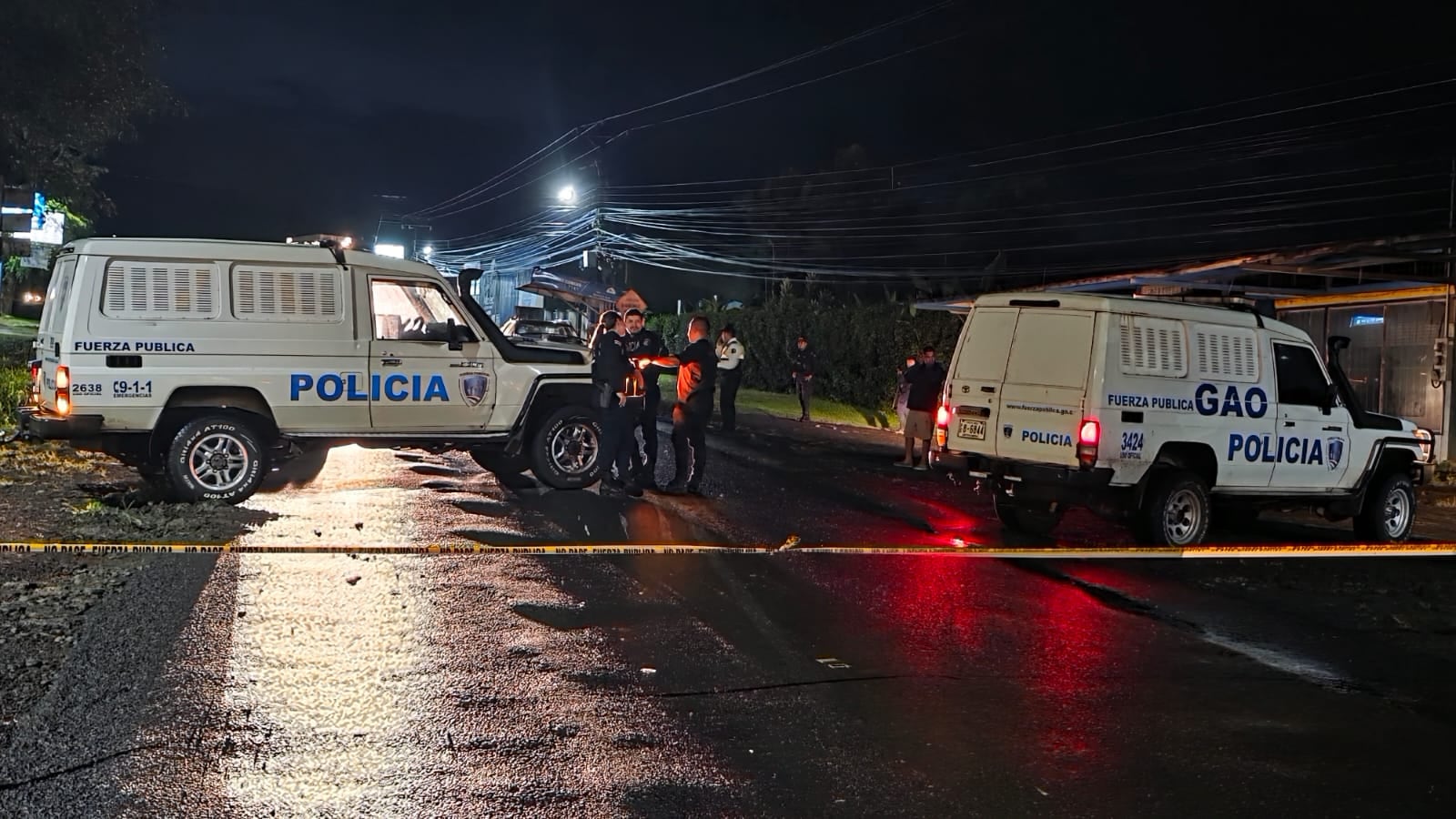 Calle cerrada, carros de la Fuerza Pública, cinta amarilla. Policías revisando la escena.