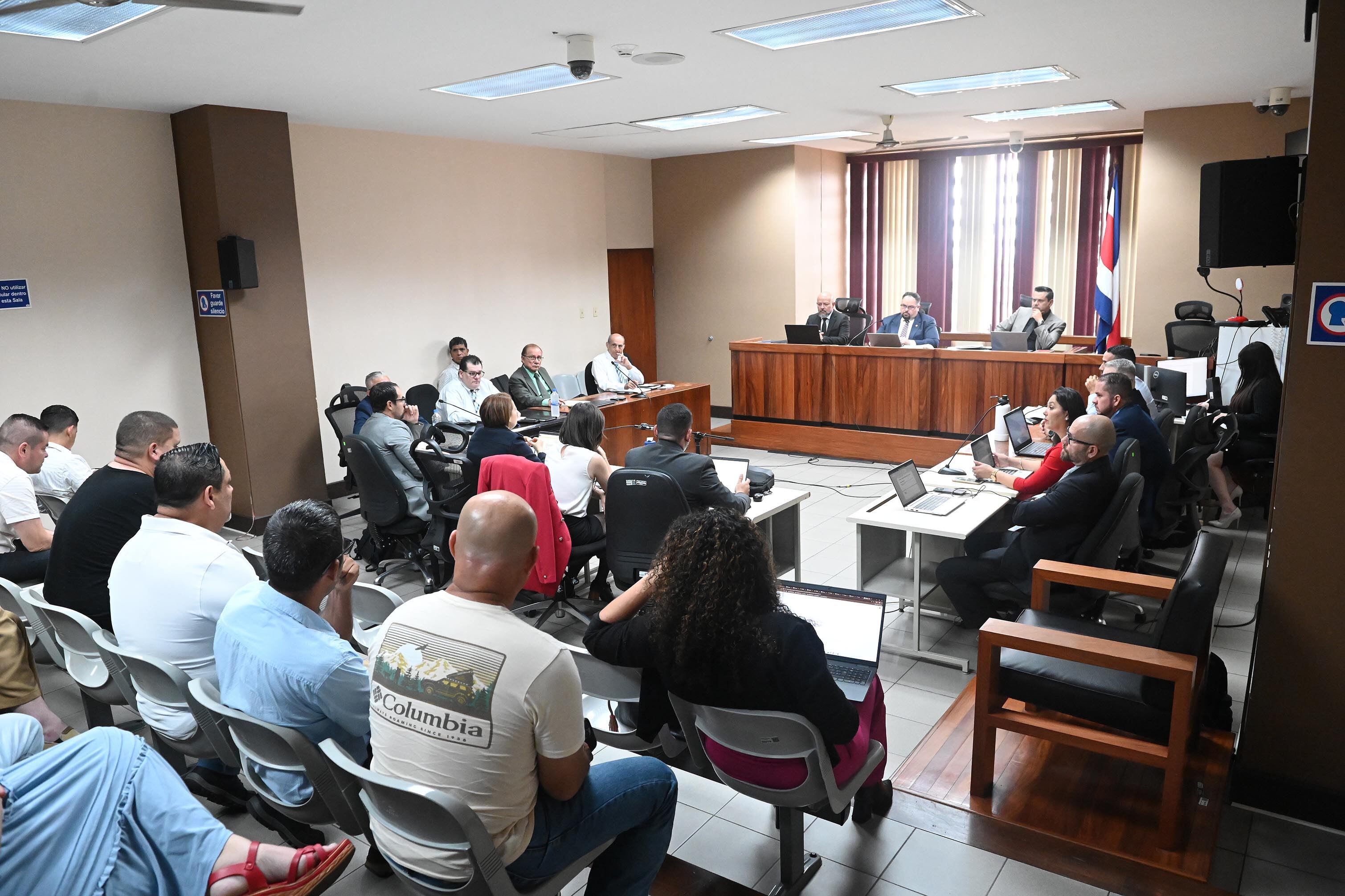 28 de mayo del 2025. Tribunales de Goicoechea. 13:00 hrs. Un nuevo tribunal encabezado por el juez Alexander Salazar decidió aplazar por un mes mas el juicio que se sigue por el caso de la Trocha. A solicitud de los defensores de los  acusados quienes argumentaron poco o nulo conocimiento del caso pues en días recientes fueron asignados para ese fin.  En la foto: El abogado Fernando Apuy (izq) escucha la intervención de la defensa.  Foto: Albert Marín .