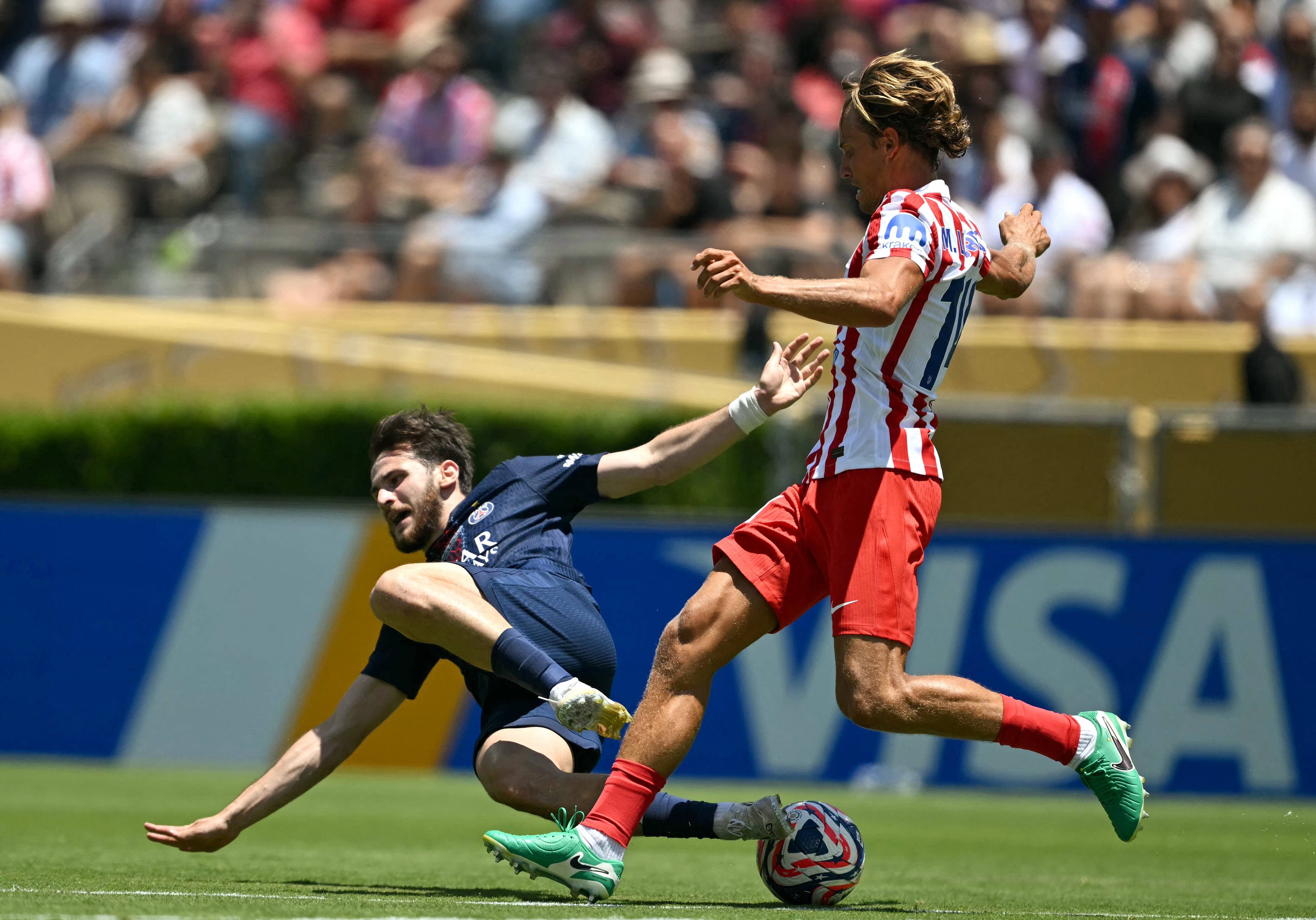 El delantero georgiano del PSG Khvicha Kvaratskhelia (izq.) disputa el balón con Marcos Llorente del Atlético de Madrid, en un pasaje el duelo por el Mundial de Clubes.
