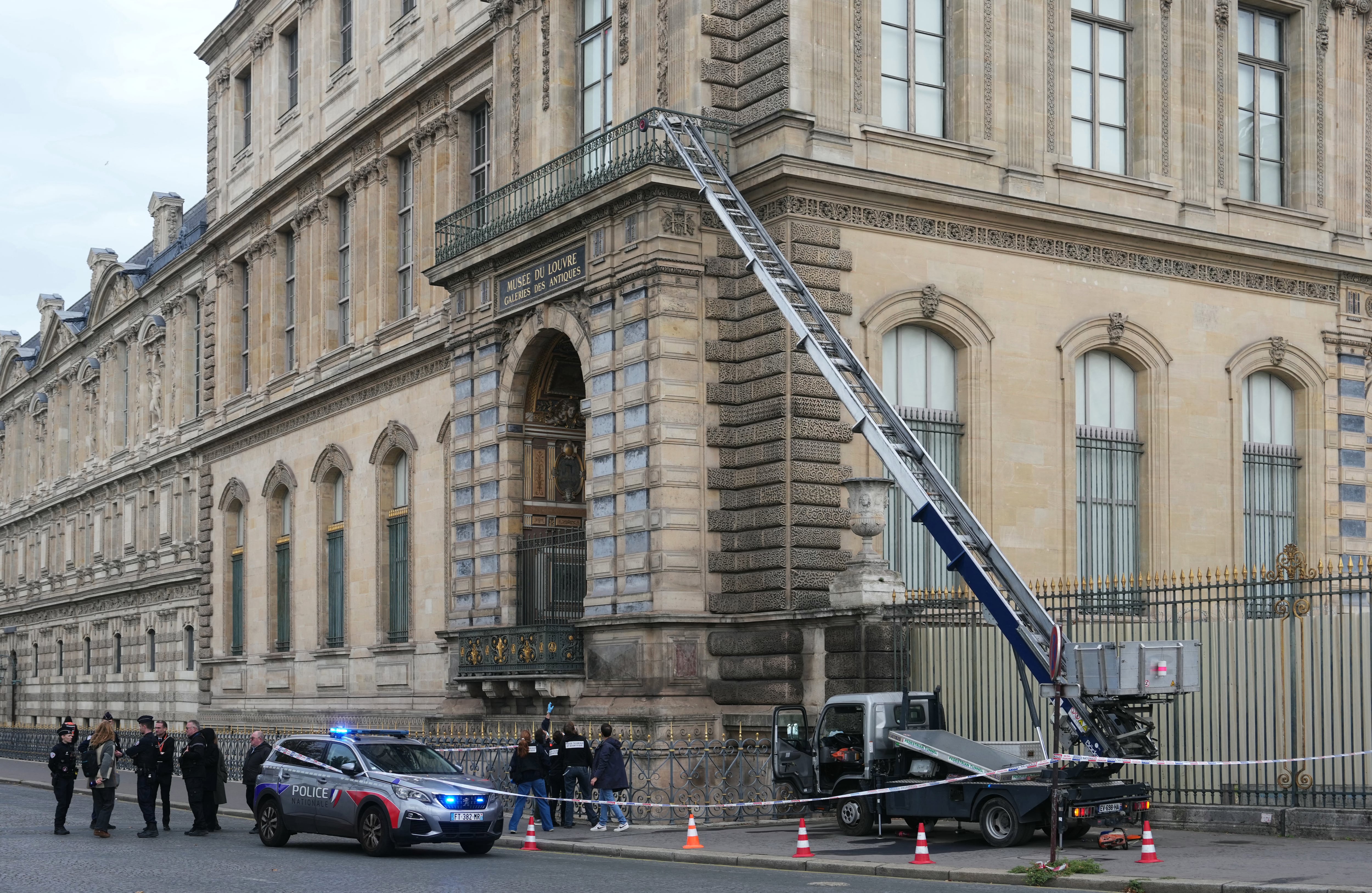 French police officers stand next to a furniture elevator used by robbers to enter the Louvre Museum, on Quai Francois Mitterrand, in Paris on October 19, 2025. Robbers broke in to the Louvre and fled with jewellery on October 19, 2025 morning, a source close to the case said, adding that its value was still being evaluated. A police source said an unknown number of thieves arrived on a scooter armed with small chainsaws and used a goods lift to reach the room they were targeting. (Photo by Dimitar DILKOFF / AFP)