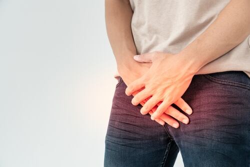 Hombre de medio cuerpo con las manos en la zona pélvica, representando dolor asociado al cáncer de próstata.