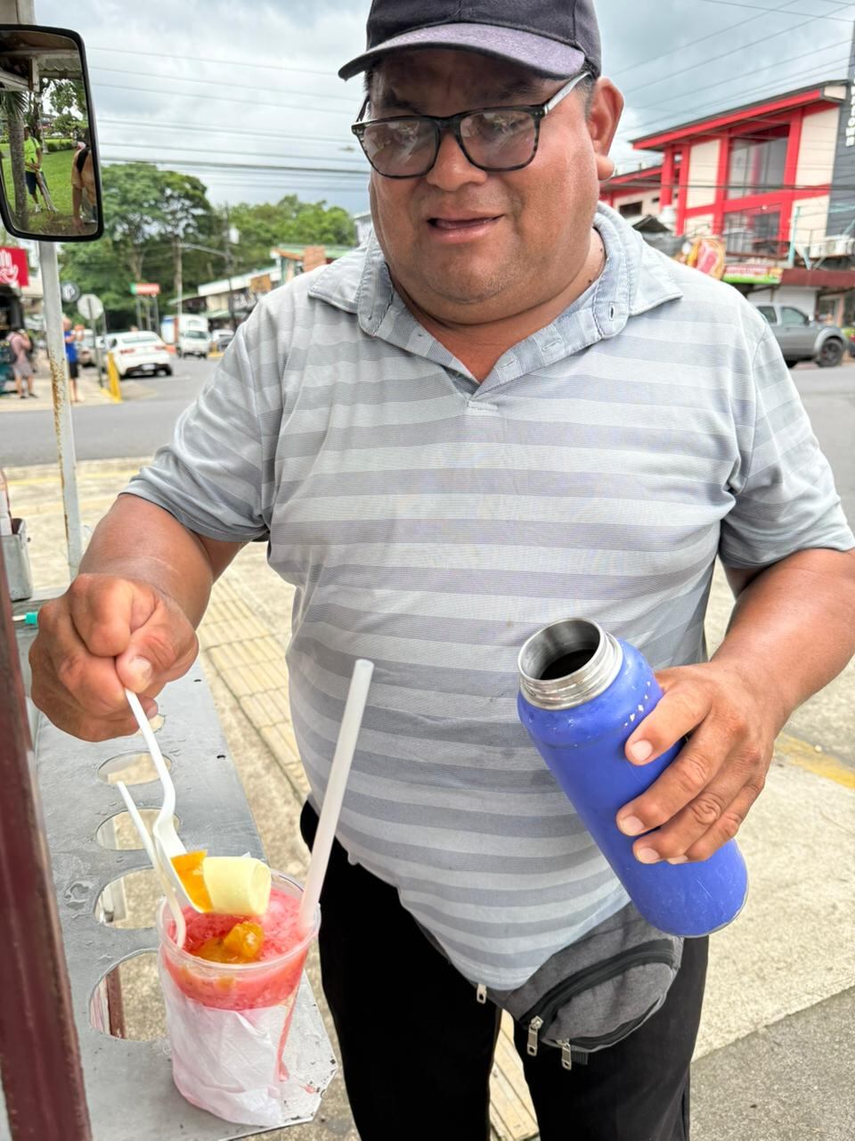 Las personas buscan dónde esconderse cuando cae un aguacero en La Fortuna de San Carlos, pero el nicaragüense, Antonio Padilla Madriz, más bien sonríe y le agradece a Dios porque así venderá más copos