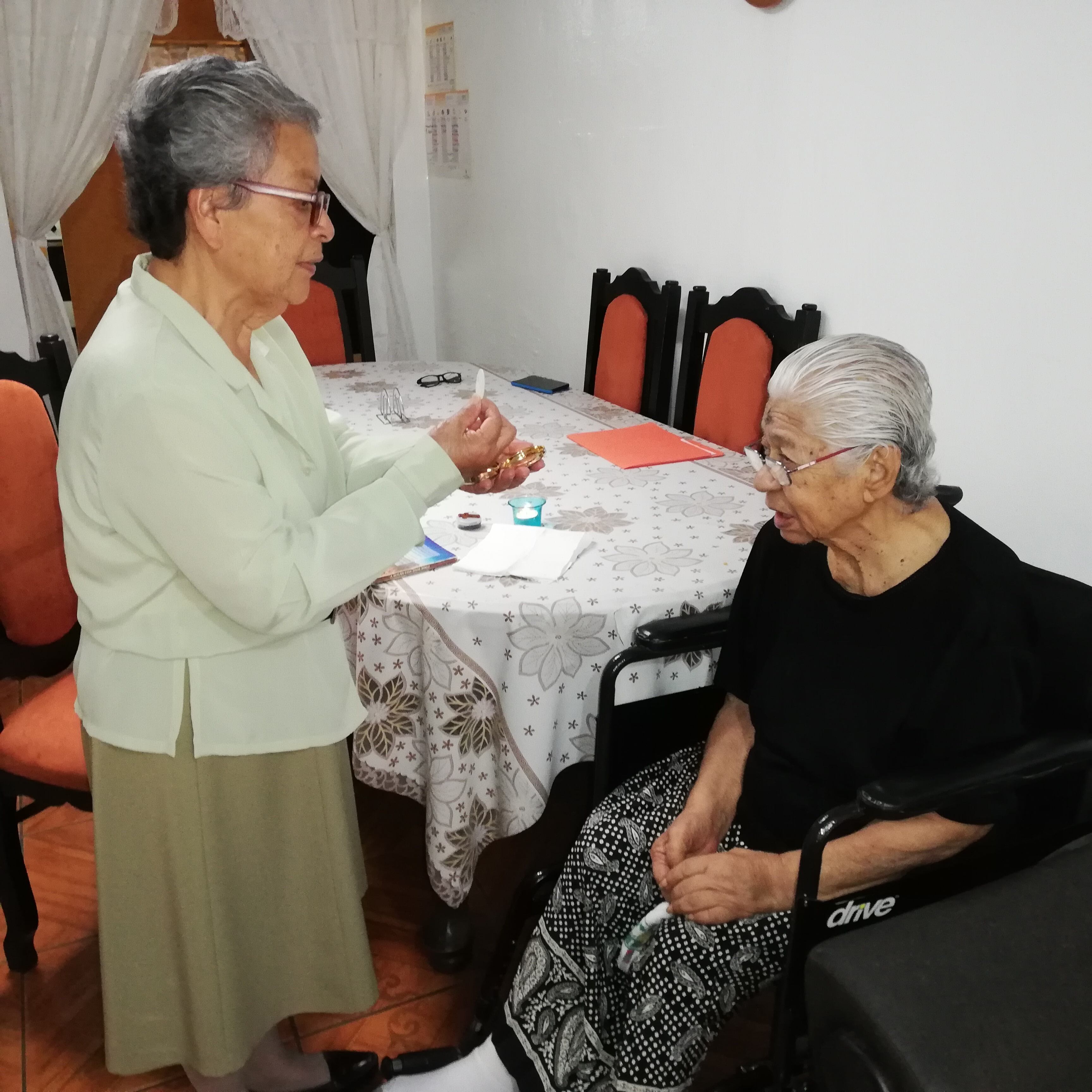 Doña Flor Román le da la comunión a doña María Delia Pizarro