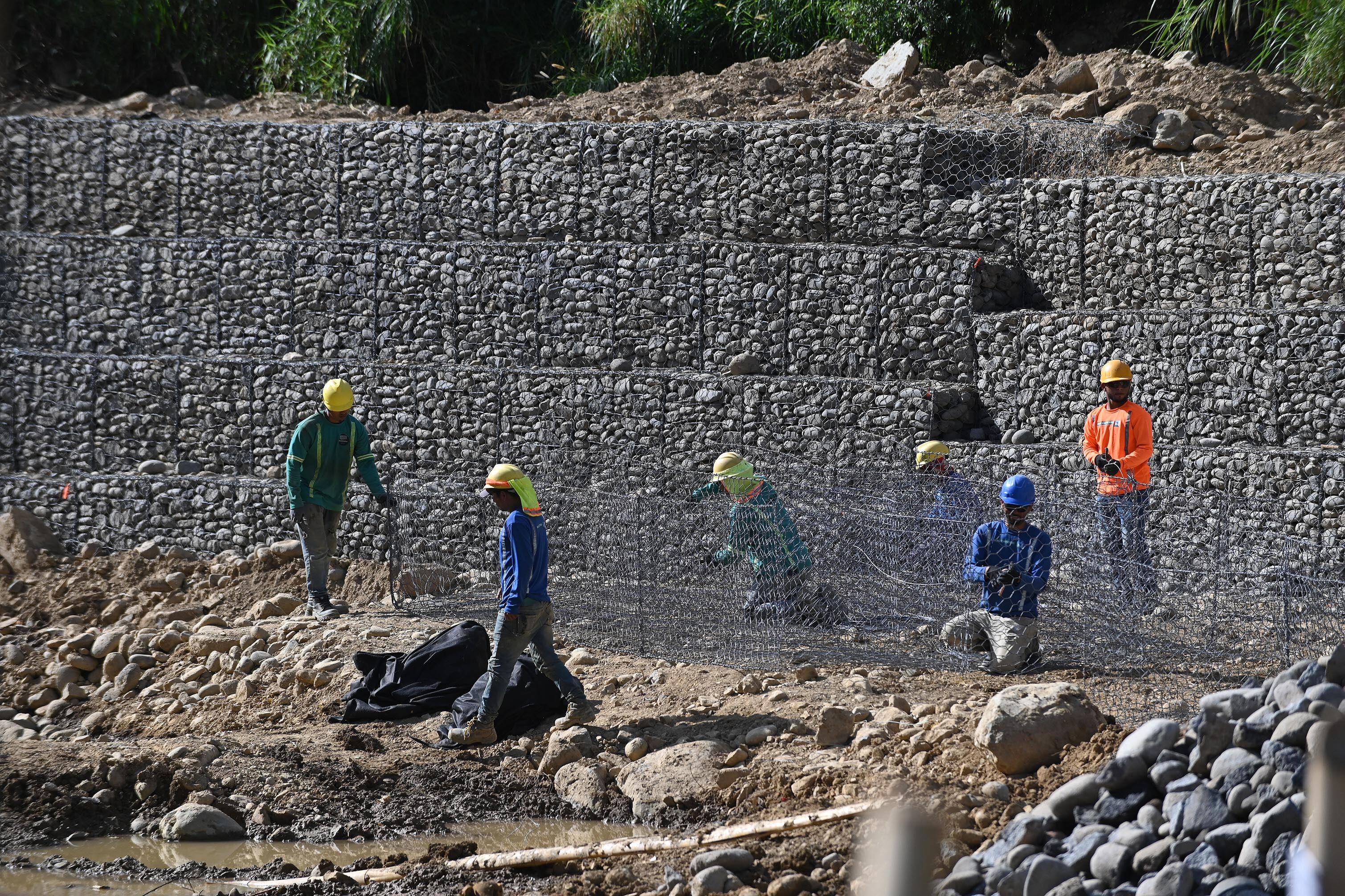 04 de abril del 2025. San Rafael Arriba de Desamparados. Río Cañas. 06:00 hrs.  Maquinaria y personal de una empresa constructora privada realizan la construcción de varios muros de retención (gaviones) a lo largo del río Cañas al sur de la capital.  La obra es financiada por el BCIE  (Banco Centroamericano de Integración Económica) y gestionada por la Comisión Nacional de Emergencias.  El proyecto beneficiaría a unas 24000 personas de comunidades como Calle Robles, San Bosco, Blanca Durán y La Granja que sufrieron serios daños con las lluvias del año anterior. Algunos vecinos del lugar externaron su molestia pues consideran que se refuerzan orillas del cauce del río pero se debilitan otras. En la foto: maquinaria pesada y personal de una constructora privada realizan las labores en el río Cañas. Foto: Albert Marín para la Nación.