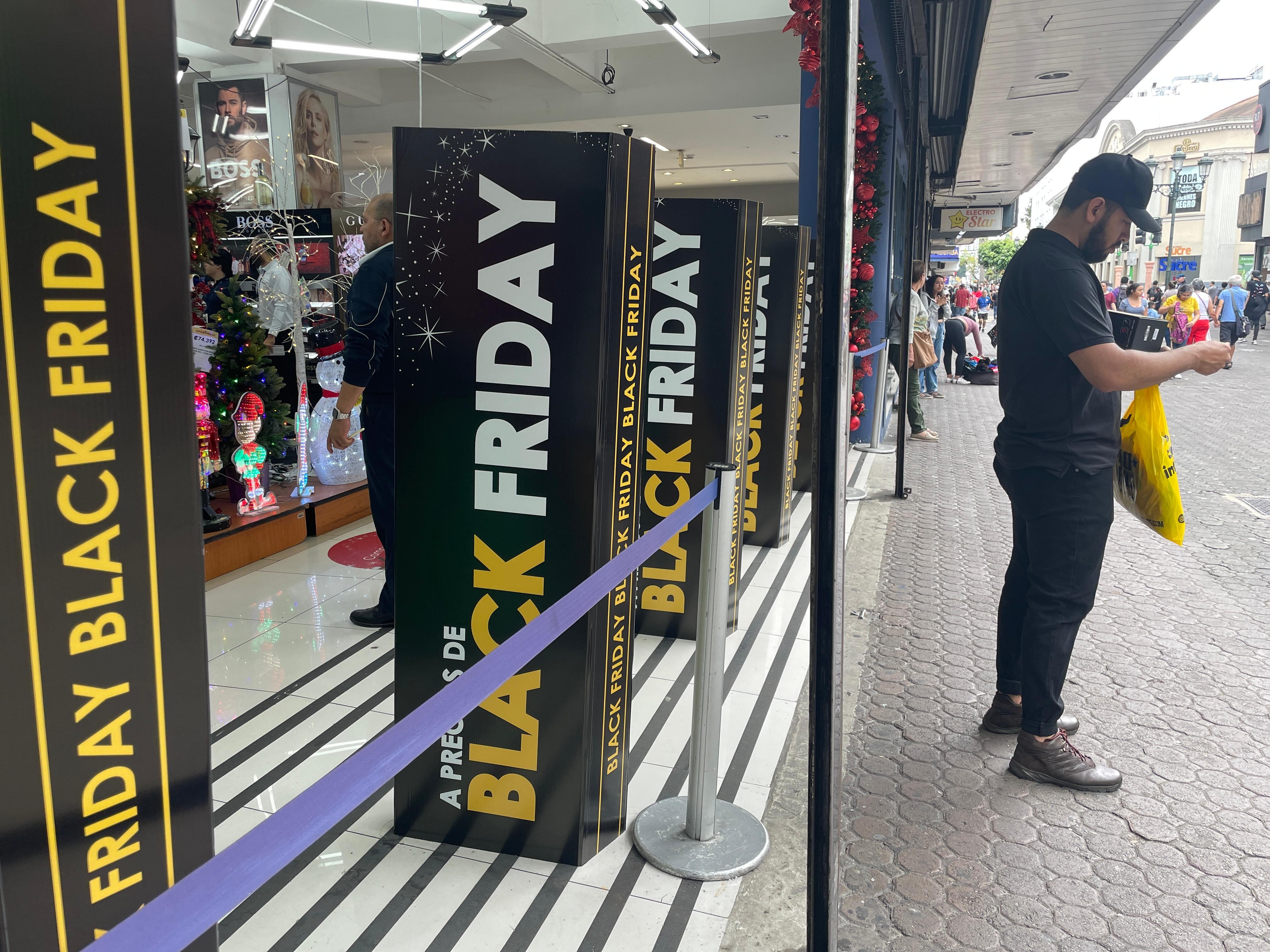Carteles de Black Friday en la entrada de una tienda decorada con motivos navideños en la Avenida Central, San José.