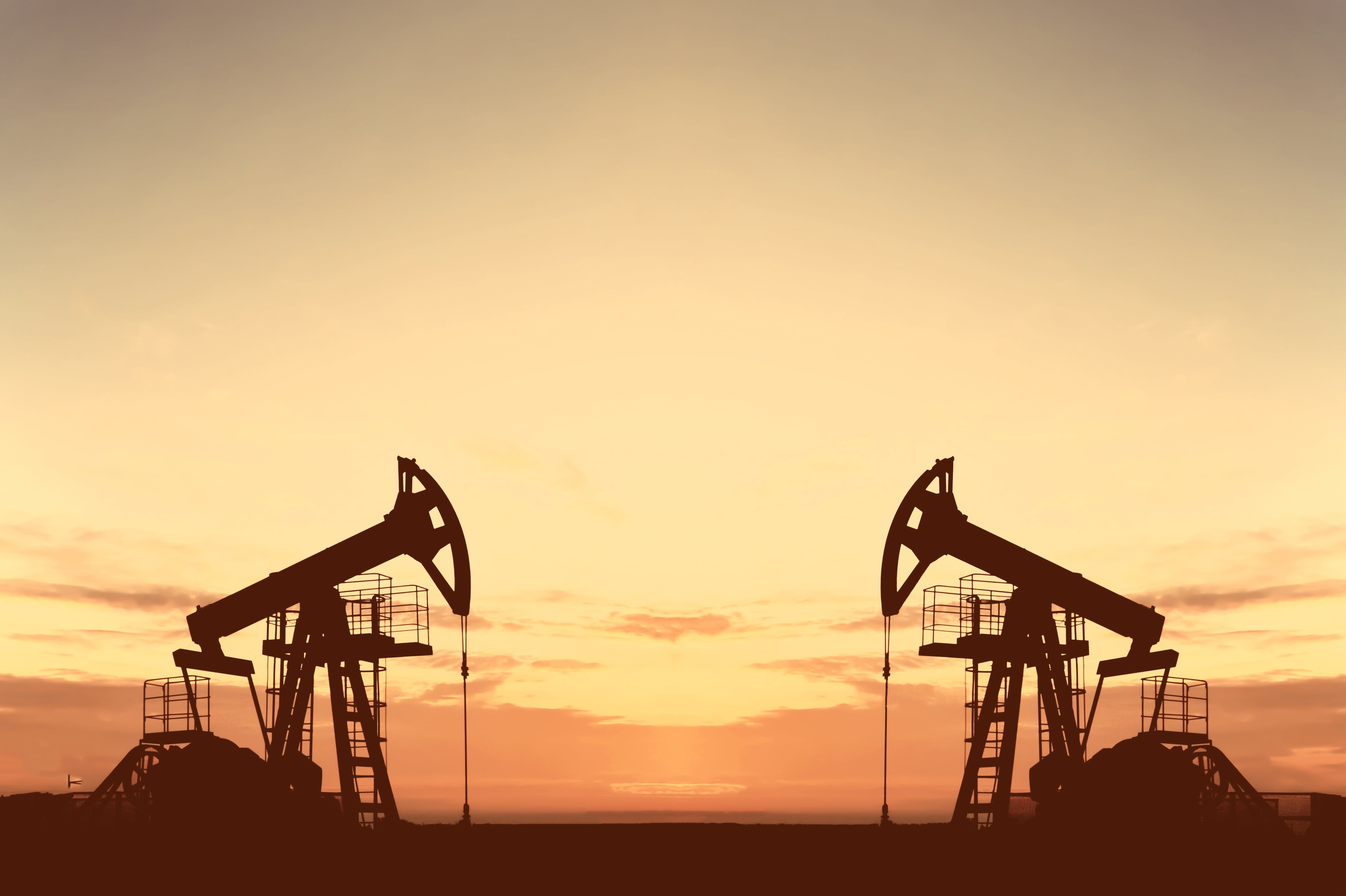 Bomba de petróleo crudo en un yacimiento petrolífero al atardecer. Producción de crudo fósil y combustibles. Plataforma petrolífera y torre de perforación. Energía, demanda de petróleo. Bomba de petróleo.