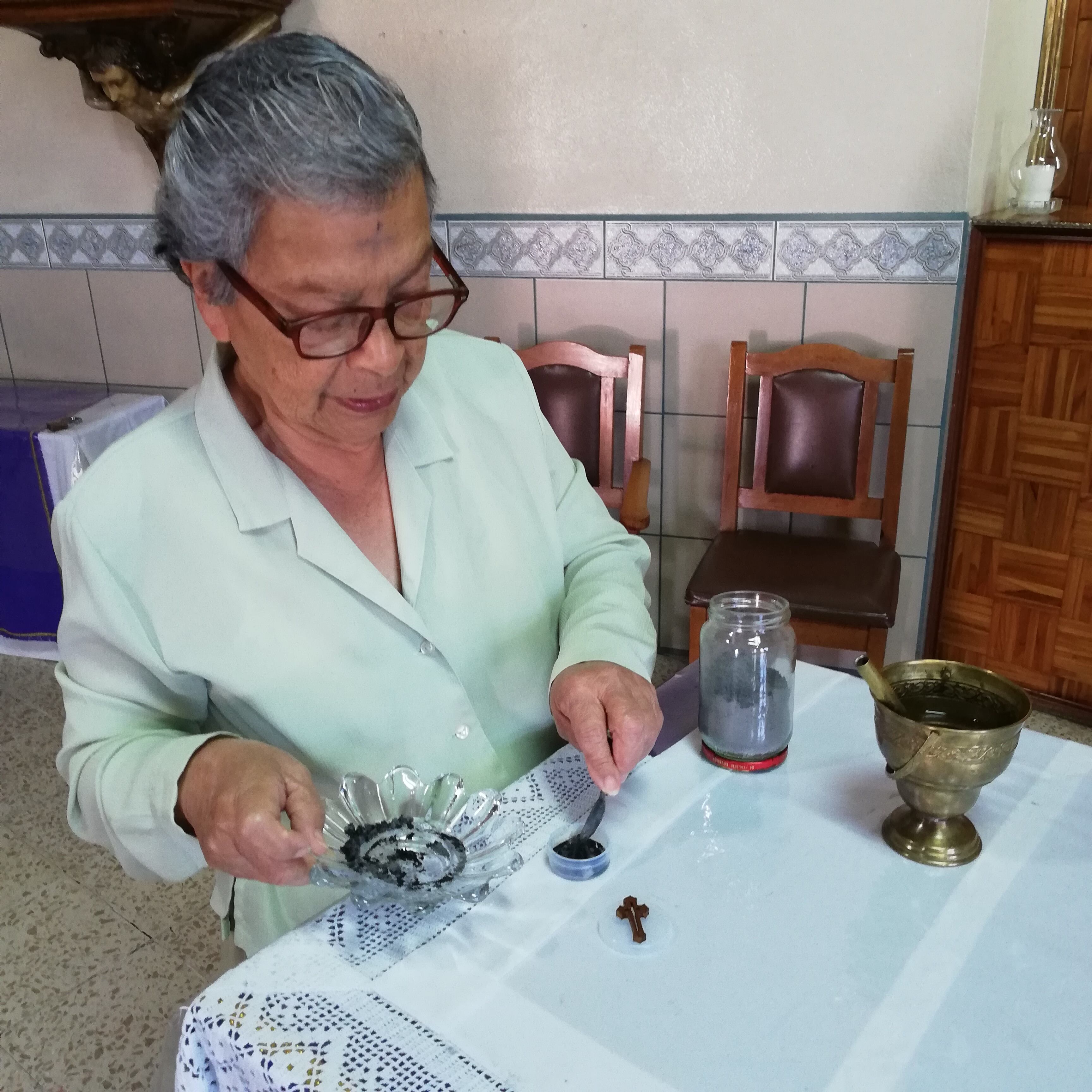 Doña Flor de María Román Chavarría humedece la ceniza con agua bendita el Miércoles de Ceniza