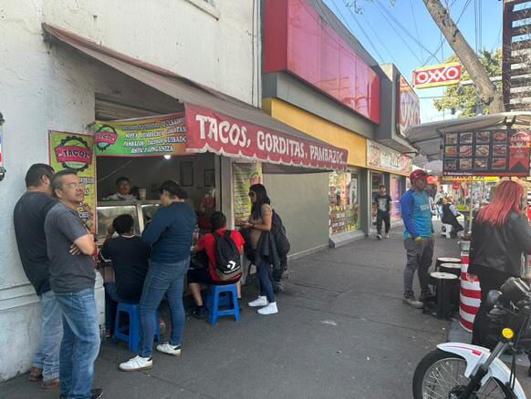 En frente de un puesto de tacos hay otro en cada esquina.
