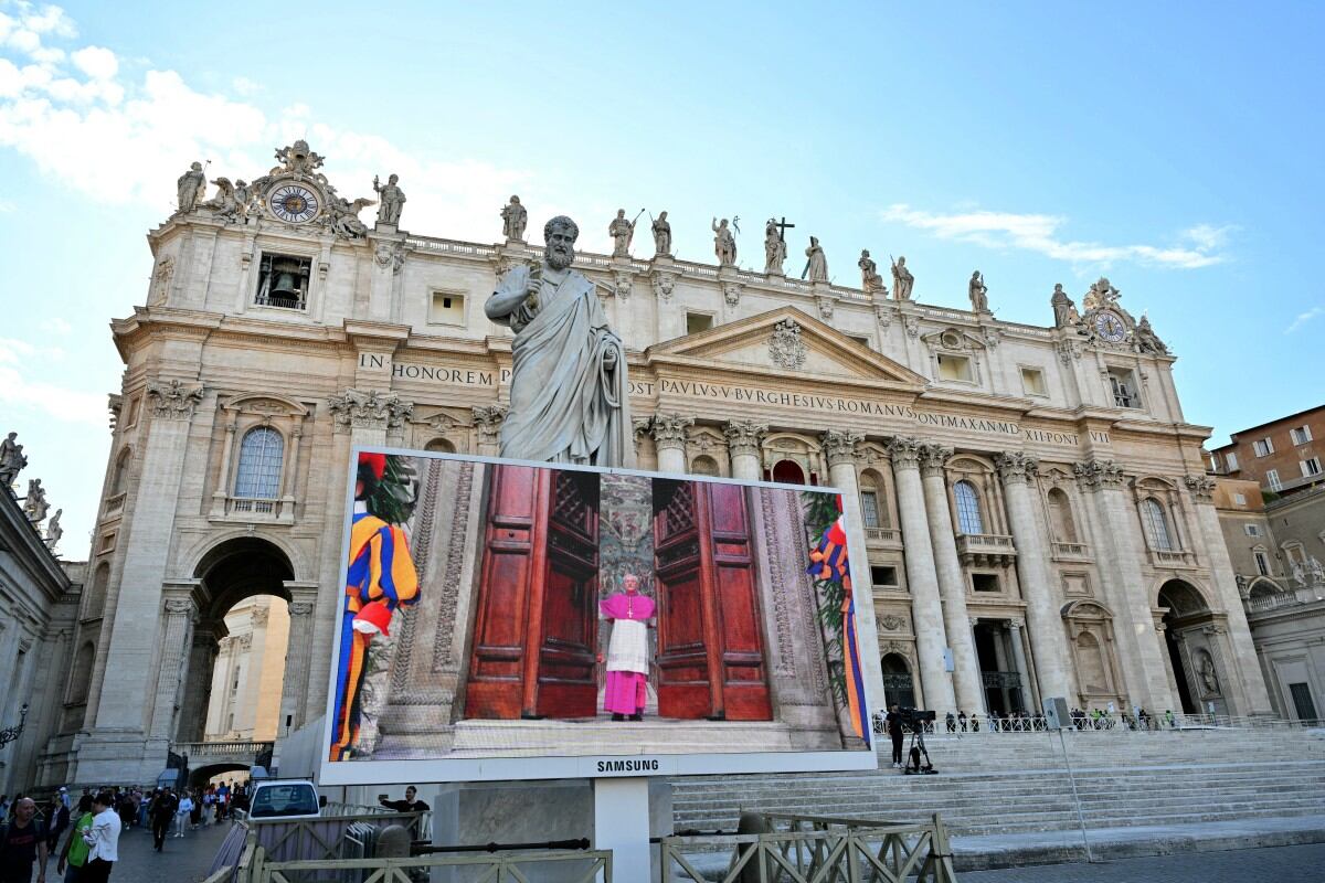 Fieles observan una pantalla gigante que muestra imágenes de Diego Giovanni Ravelli, Maestro de las Celebraciones Litúrgicas Pontificias, cerrando las puertas de la Capilla Sixtina al inicio del cónclave para elegir a un nuevo Papa, en la Plaza de San Pedro, en el Vaticano, el 7 de mayo de 2025. (Foto de Alberto PIZZOLI / AFP)