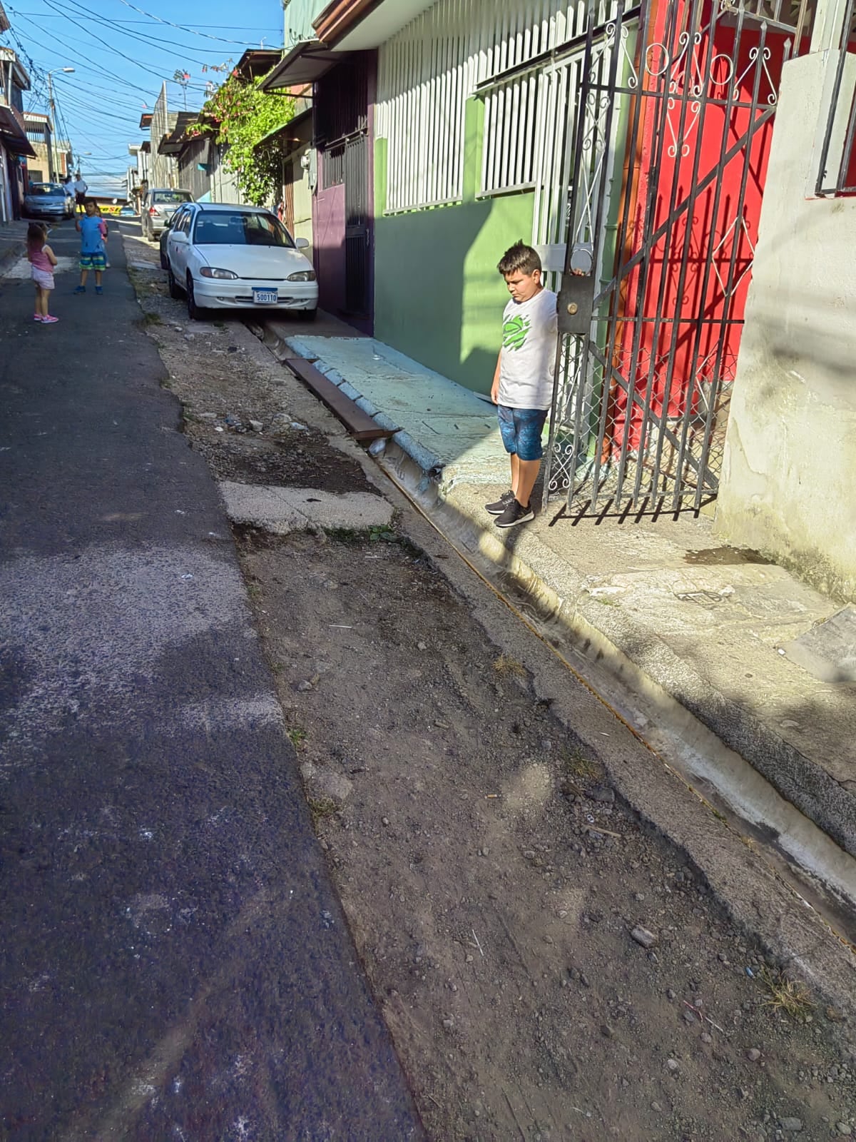 El ministro de vivienda Fernando Zumbado Jiménez con un oso de peluche, tras pasar la noche en un tugurio de Lomas del Río, Pavas, el 29 de mayo del 2007. En la foto Johan Andrei Alvarado Morales, de 11 años, muestra lo mal que está la calle de la alameda donde vive en Finca San Juan de Pavas.