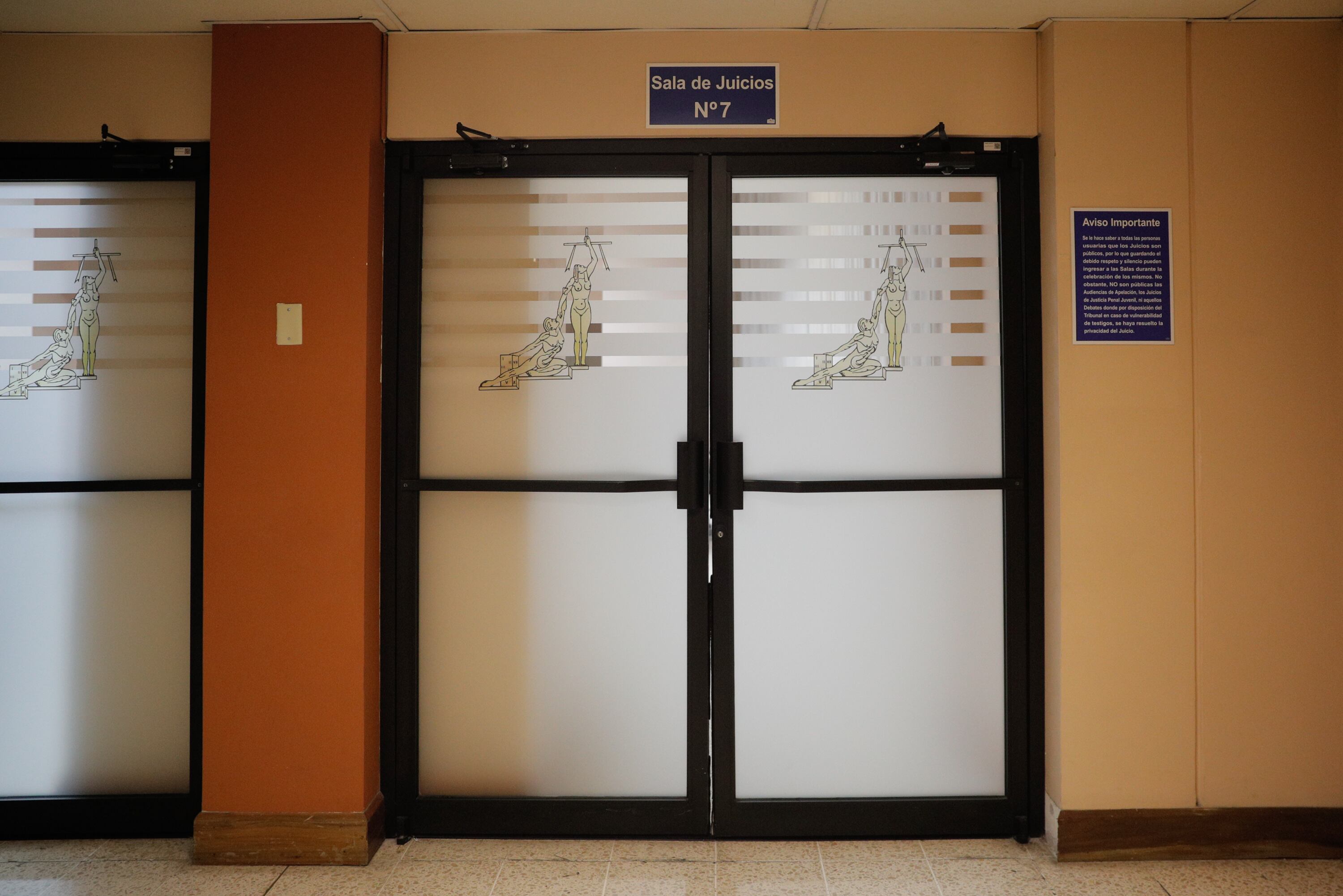 Puerta con rótulo "Sala de Juicios", flanqueada por figuras simbólicas: mujer desnuda con balanza de la justicia y hombre a sus pies