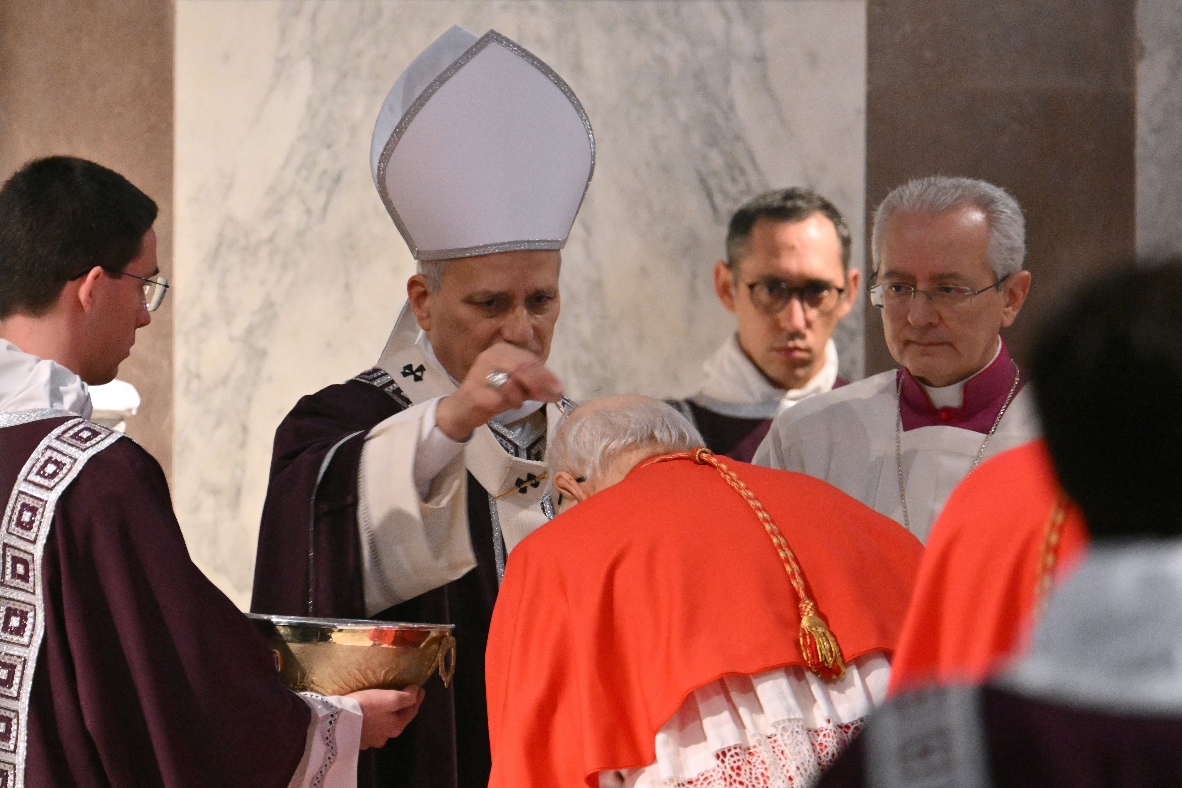 Pope Leo XIV sprinkles the head of a Cardinal with ashes during the celebration of Ash Wednesday at the Church of Saint Sabina in Rome on February 18, 2026. (Photo by Alberto PIZZOLI / AFP)