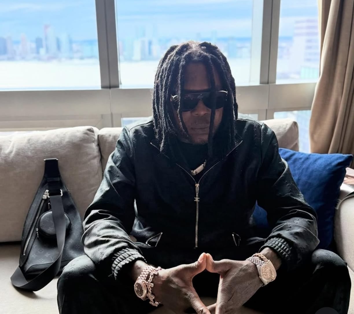 Vybz Kartel sentado con las manos entrelazadas.