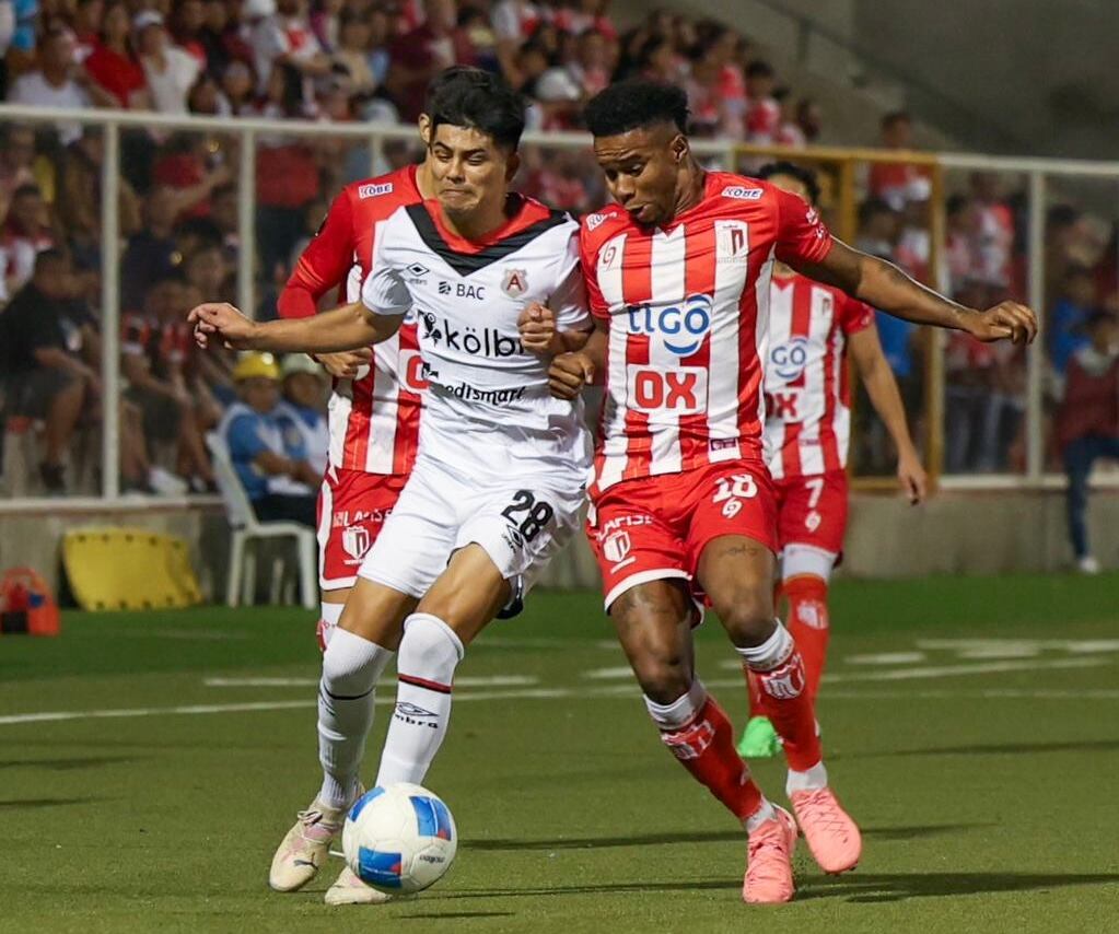 Joshua Navarro, de Alajuelense, intenta resistir la marca de William Parra, del Real Estelí (der.).