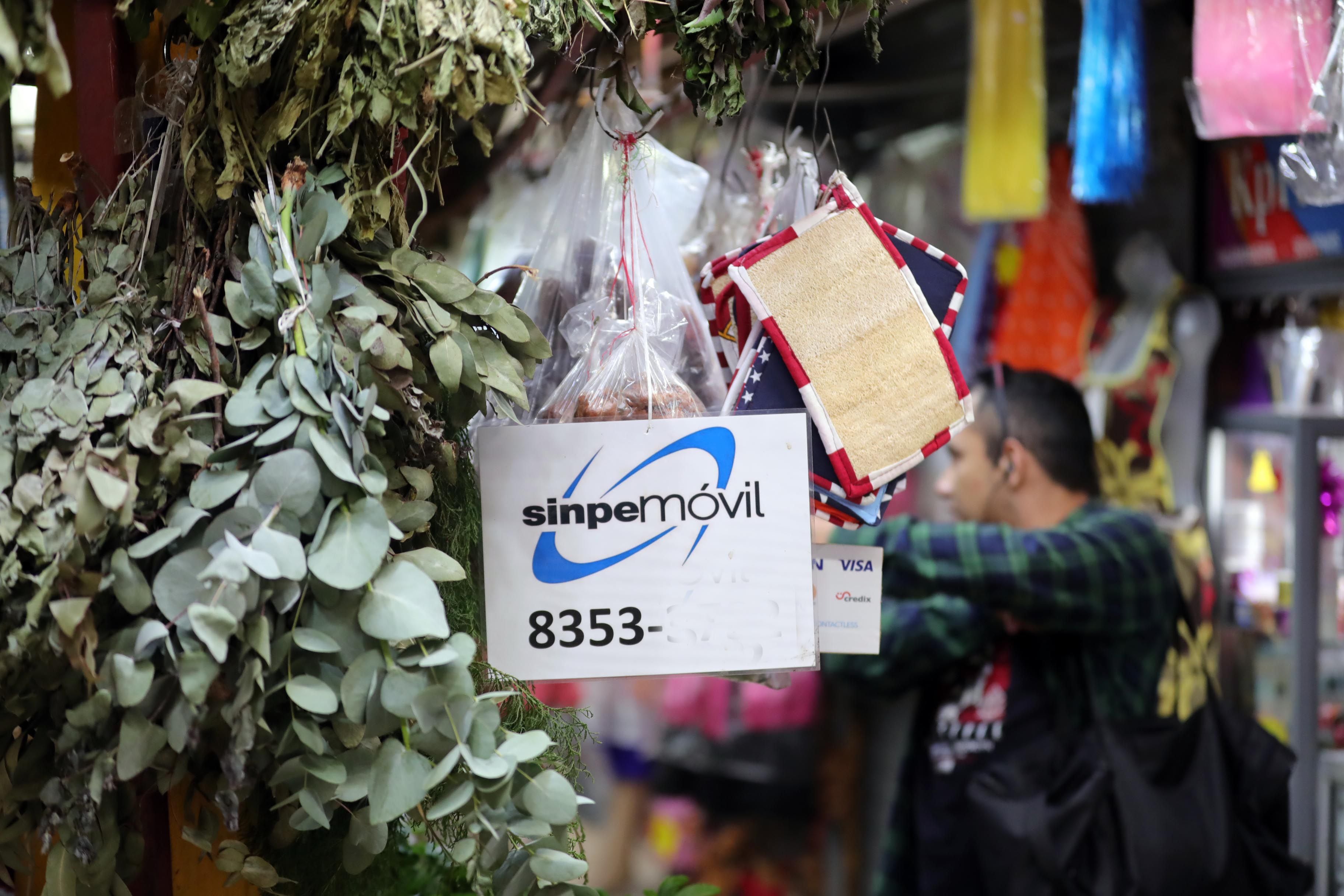 En la imagen, la vista de productos y un letrero promocionando Sinpe Móvil en un comercio local.
