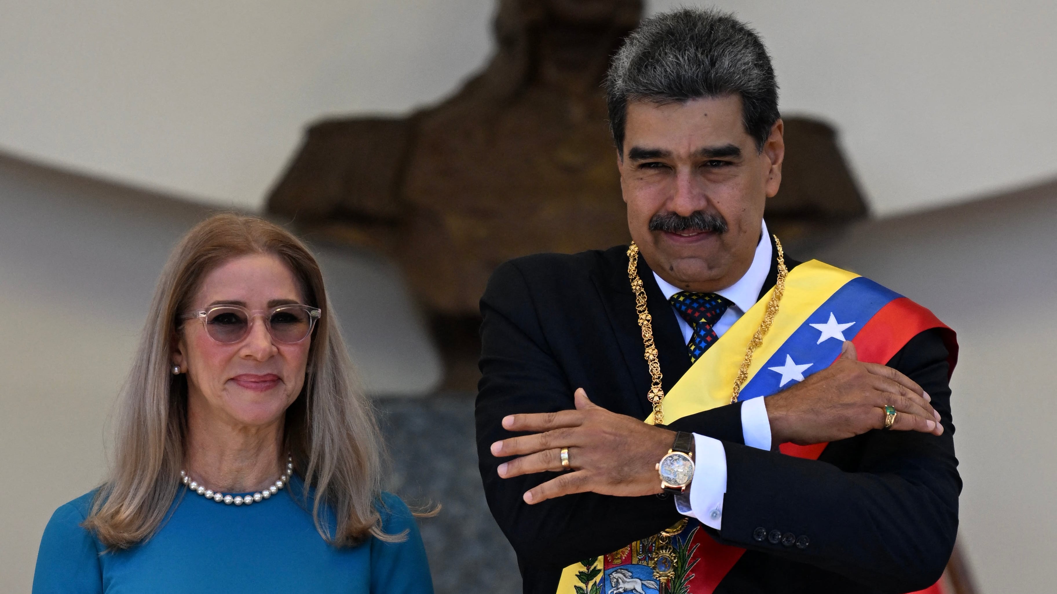 Nicolás Maduro junto a la primera dama Cilia Flores durante la ceremonia de juramentación para su tercer mandato presidencial en Venezuela, en Caracas, el 10 de enero de 2025. Maduro viste la banda presidencial y realiza un gesto simbólico.