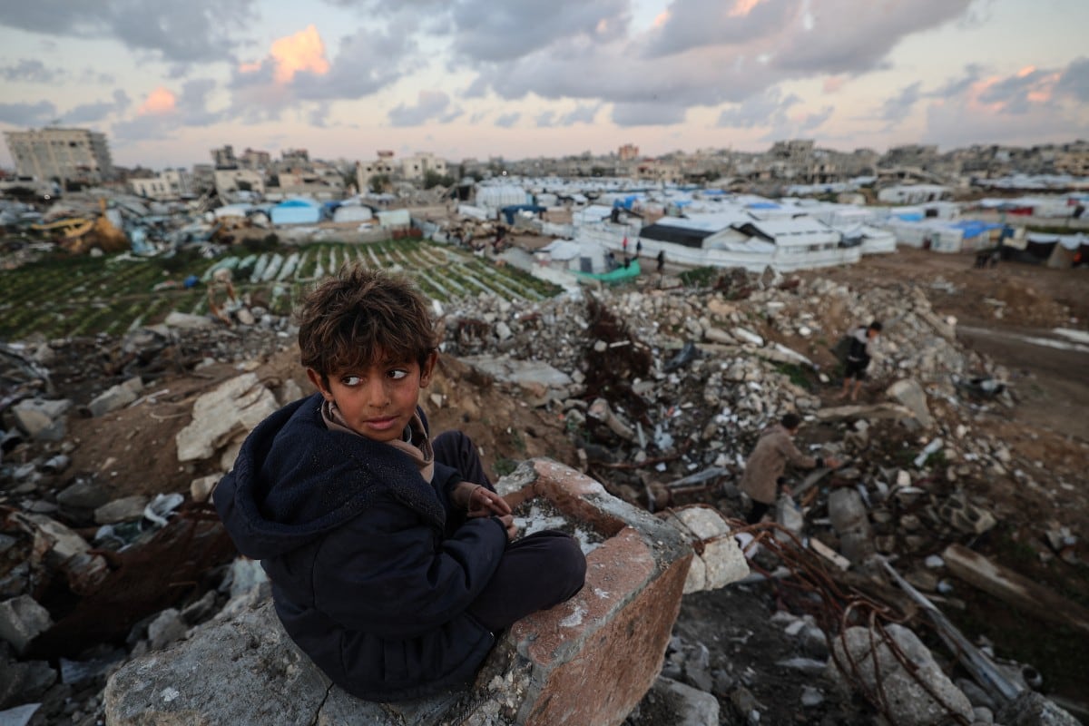 Un niño palestino permanece sentado sobre los escombros, observando tiendas de campaña y refugios improvisados en el campamento de refugiados de Bureij, en el centro de la Franja de Gaza, el 3 de febrero de 2026.