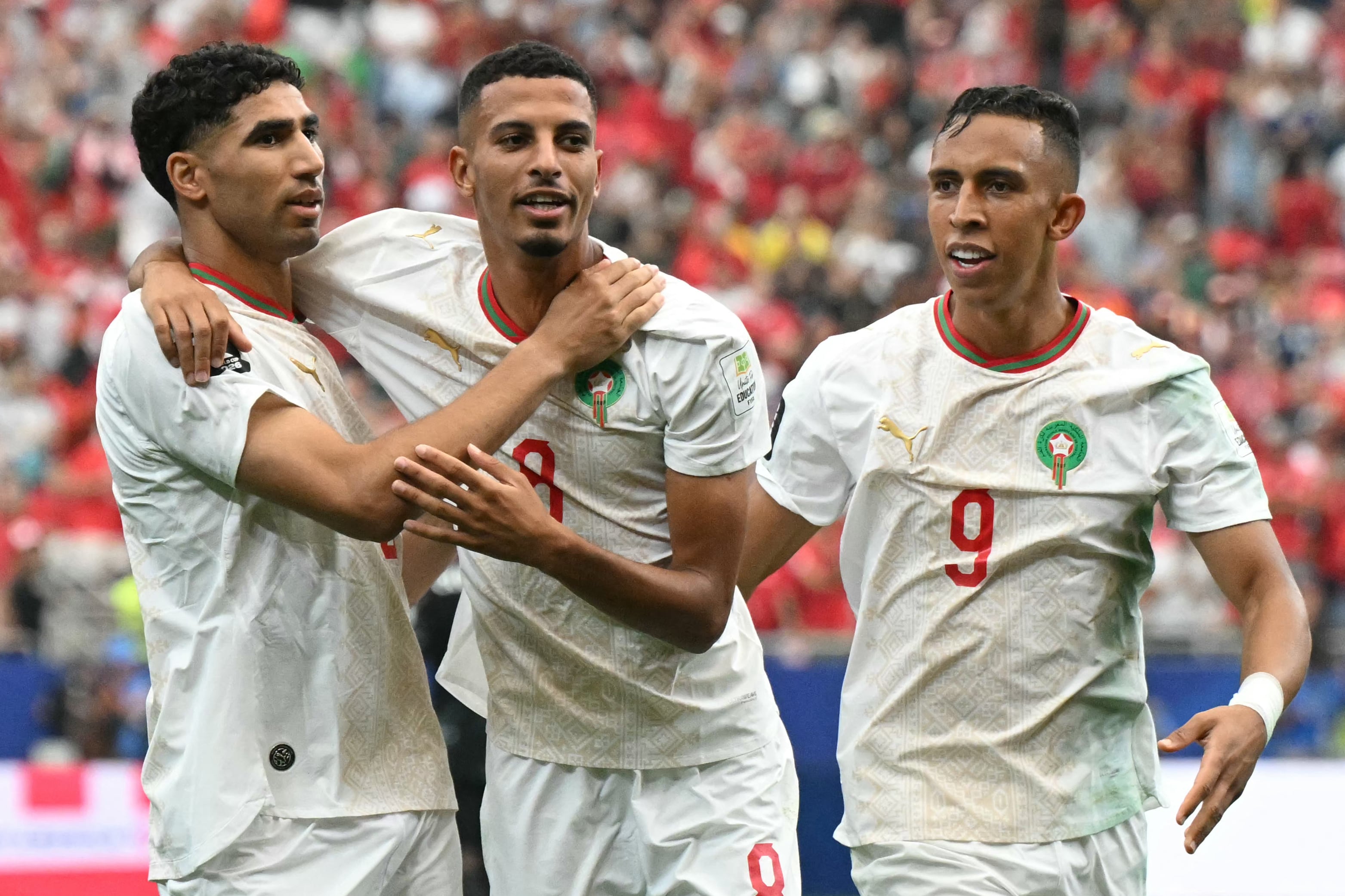 Morocco's midfielder #08 Azzedine Ounahi (C) celebrates scoring his team's first goal with teammates defender #02 Achraf Hakimi (L) and forward #09 Soufiane Rahimi (R) during the 2026 World Cup round of 16 football match between Canada and Morocco at the Houston Stadium in Houston on July 4, 2026. (Photo by RONALDO SCHEMIDT / AFP)