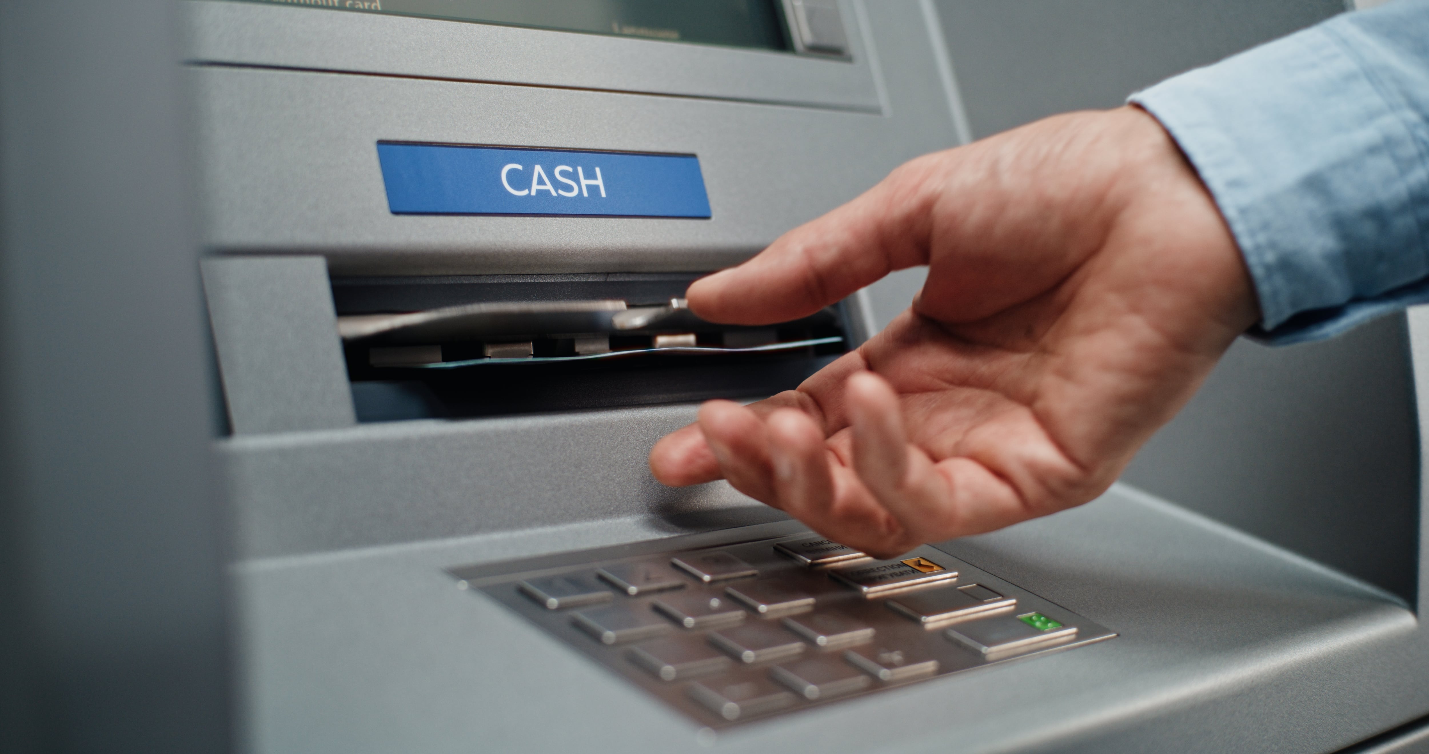 Persona saca dinero de un cajero.