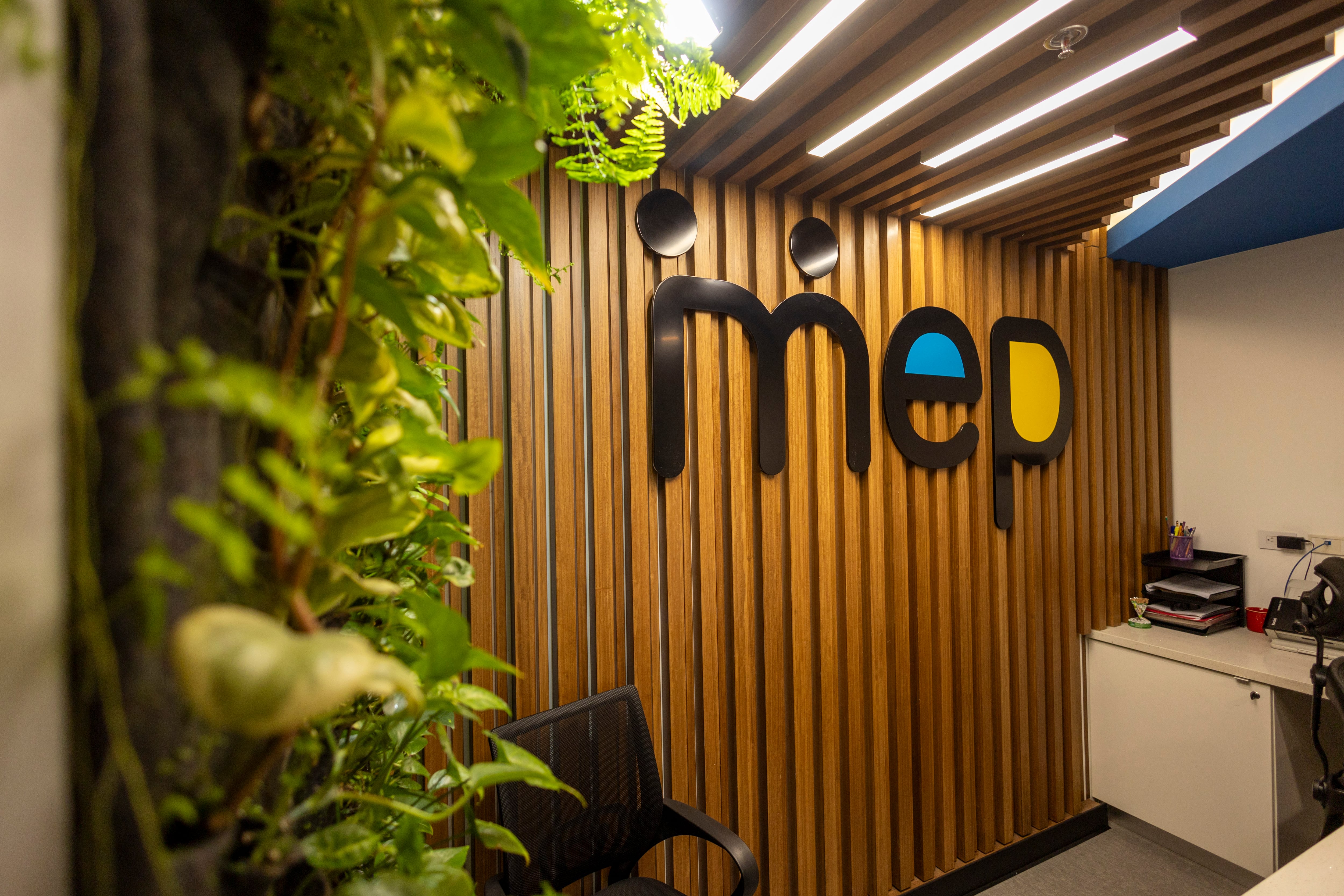 Logo del Ministerio de Educación Pública (MEP) en la pared principal de su sede central, acompañado de elementos decorativos naturales.