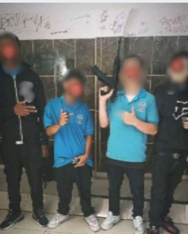 Estudiantes posan con una ametralladora