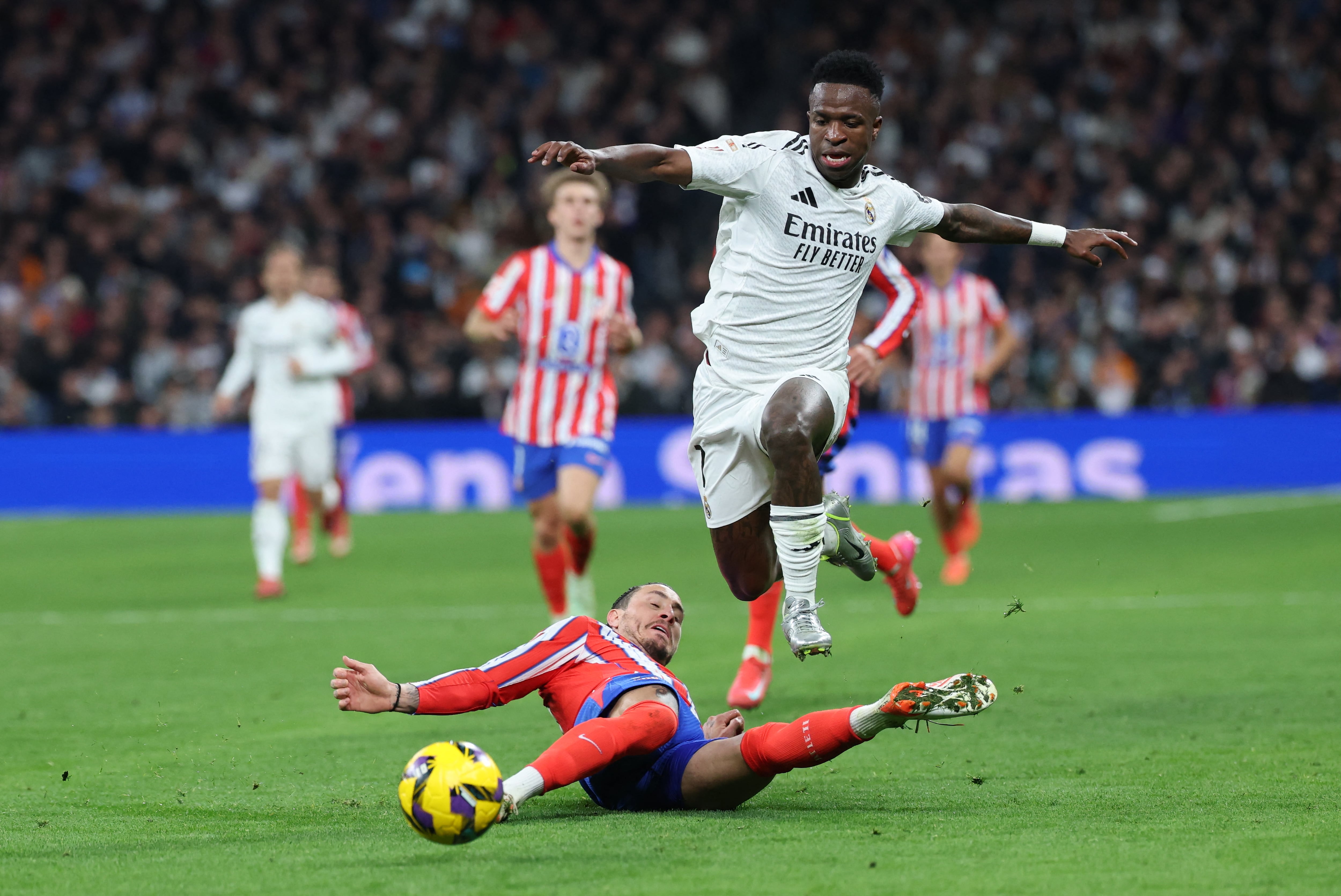 Real Madrid's Brazilian forward #07 Vinicius Junior (R) runs over Atletico Madrid's Uruguayan defender #02 Jose Gimenez during the Spanish league football match between Real Madrid CF and Club Atletico de Madrid at Santiago Bernabeu Stadium in Madrid on February 8, 2025. (Photo by Thomas COEX / AFP)
