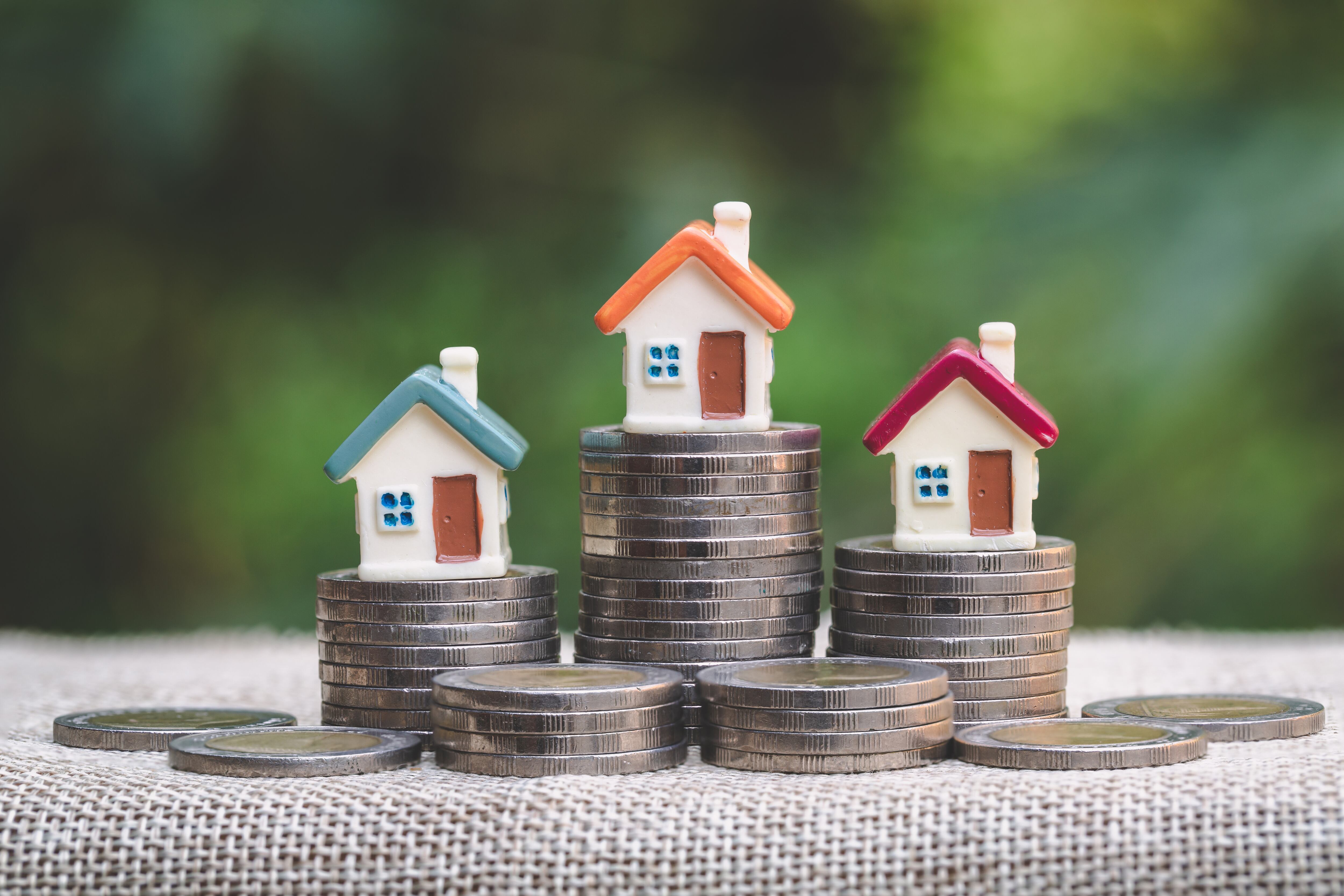 Casas en miniatura sobre pilas de monedas simbolizando el costo de acceso a la vivienda de clase media en Costa Rica y la necesidad de financiamiento.