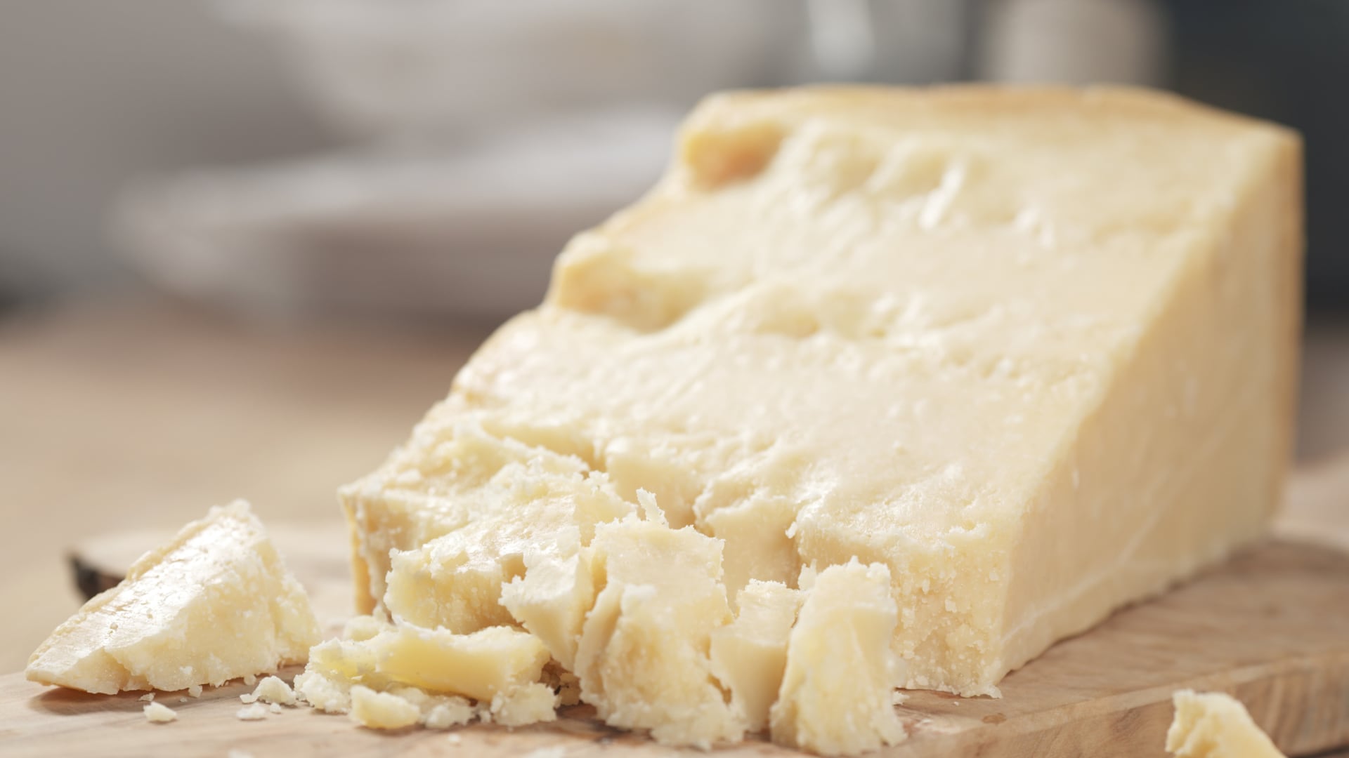 Bloque de queso semiduro sobre una tabla de madera con trozos desmenuzados, representando el producto retirado del mercado por contaminación con Listeria monocytogenes.