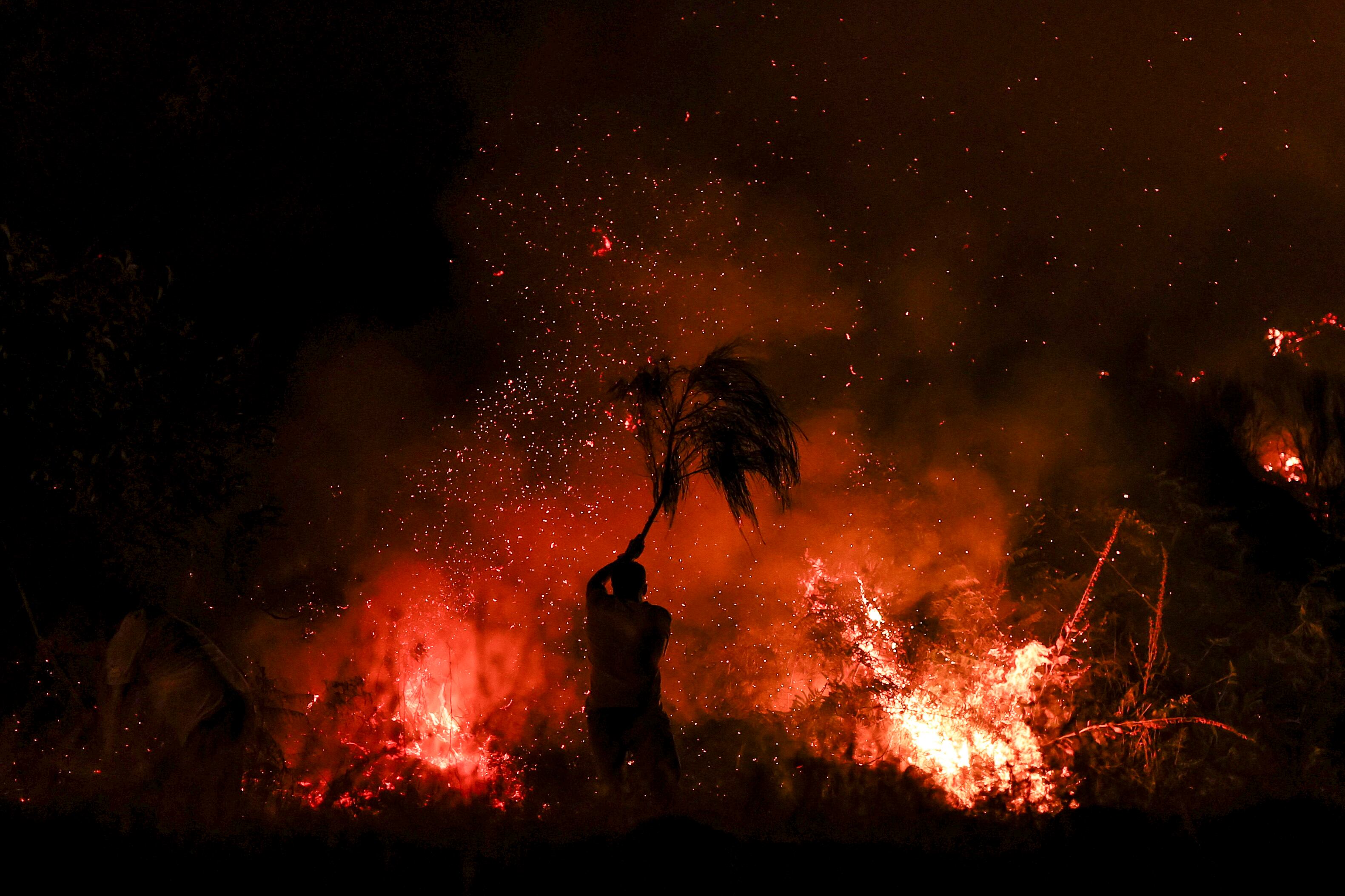 Un hombre intentó extinguir un incendio forestal con una rama en Trancoso, Portugal, este 12 de agosto. En Portugal, los bomberos combatían tres grandes incendios forestales en el centro y norte del país con más de 650 bomberos y apoyo de seis aeronaves en el mayor de ellos. Fotografía: