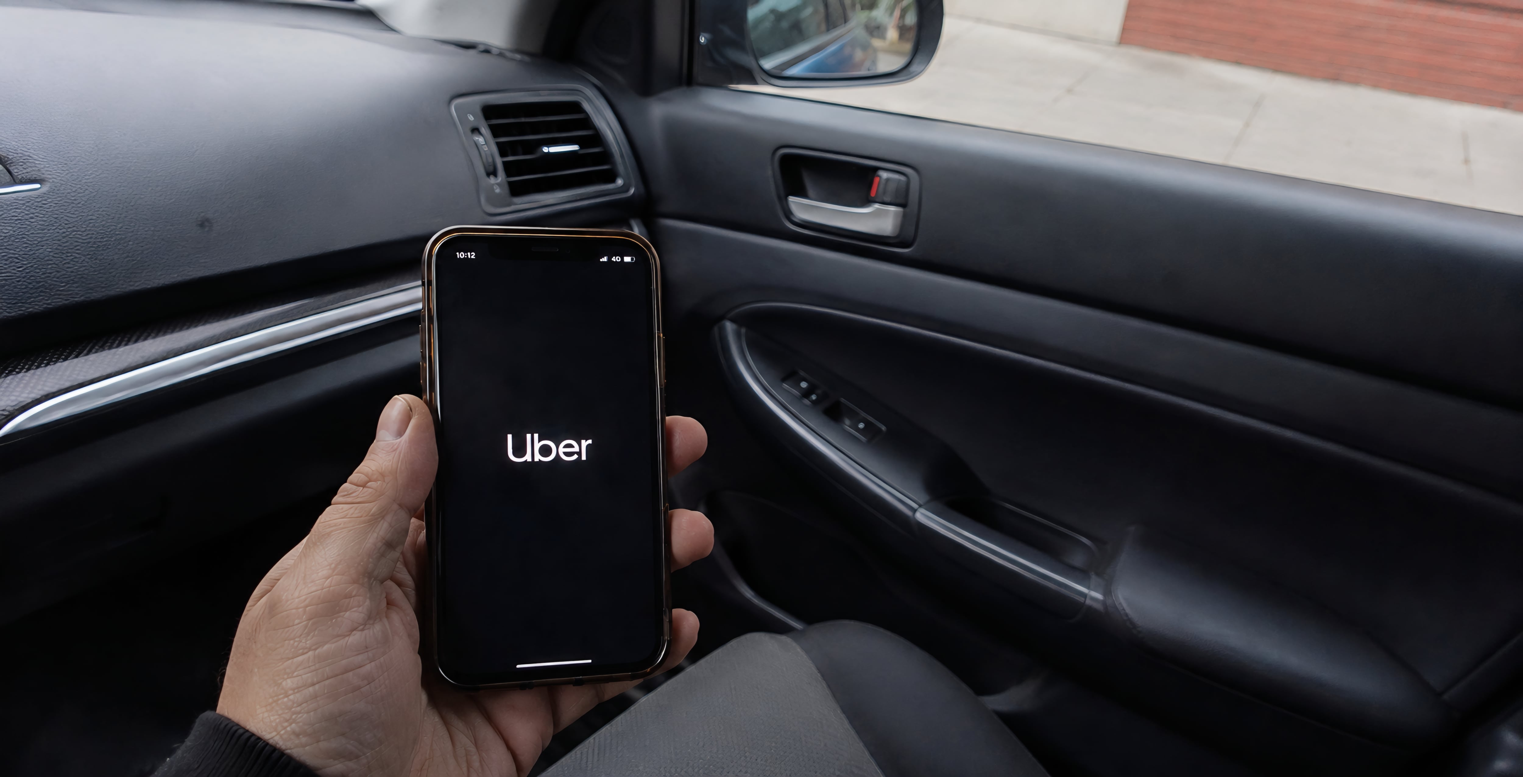 Sosteniendo un celular con la aplicación Uber abierta dentro de un carro