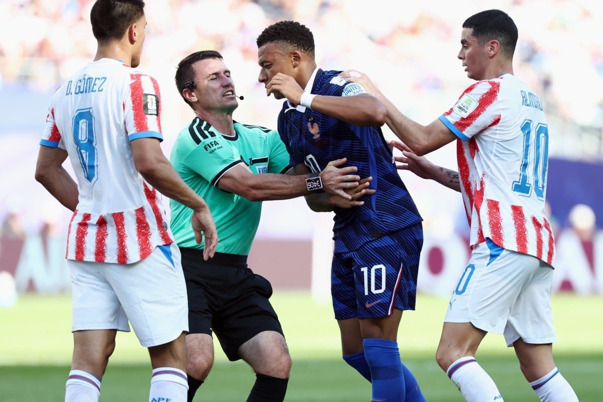 El árbitro Ilgiz Tantashev sostiene a Mbappé en un reclamo que hizo el capitán francés ante Paraguay.