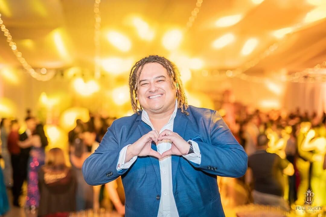 Choché Romano haciendo una seña de amor con sus manos.