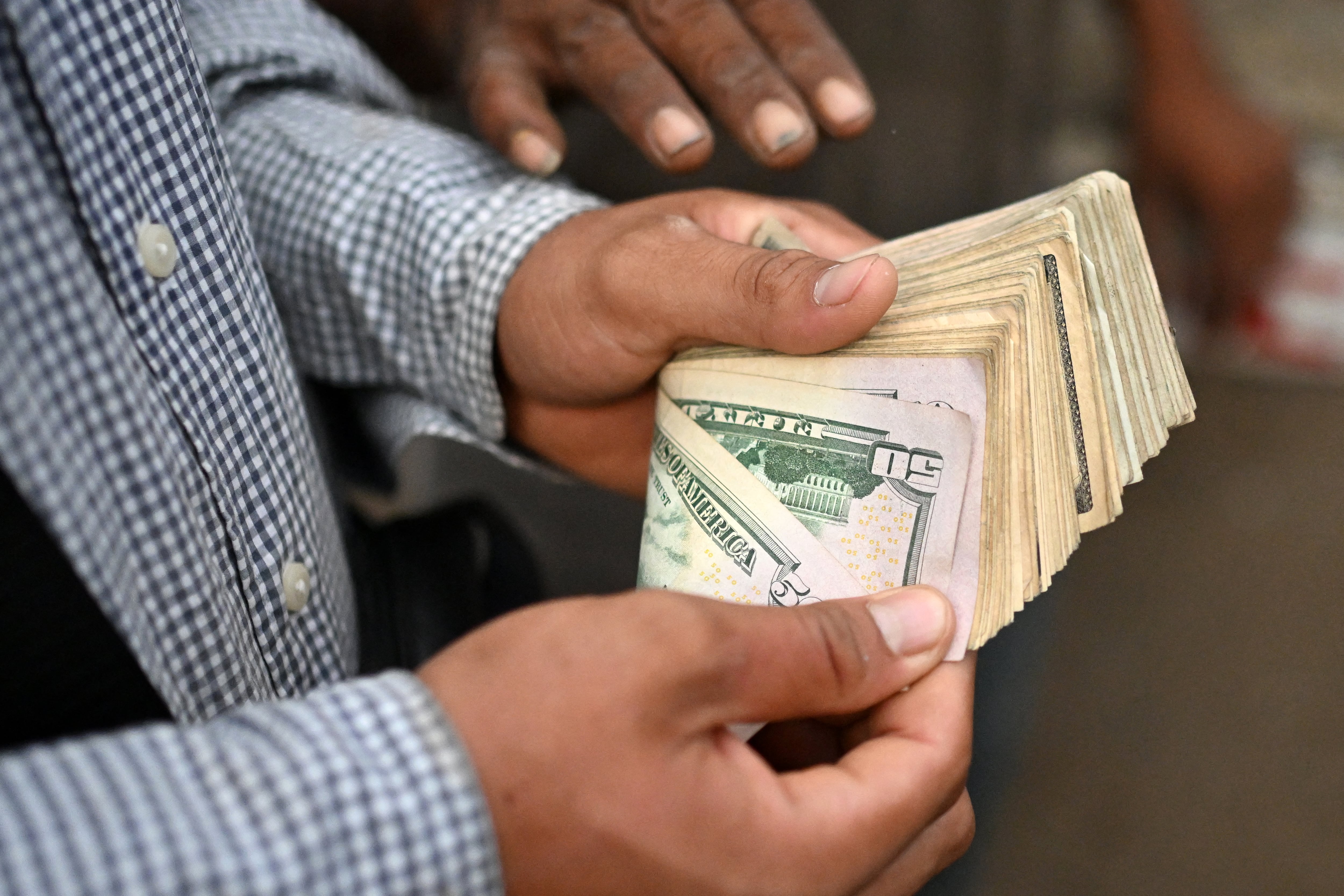 Un ganadero cuenta dinero en efectivo tras vender su ganado en el mercado municipal conocido como el Tiangue, en San Rafael Cedros, departamento de Cuscatlán, El Salvador, el 18 de abril de 2026.
En el tradicional mercado de San Rafael Cedros, que se extiende por un área cercana al tamaño de dos campos de fútbol, se compran y venden reses, caballos, cerdos, conejos, aves de corral y cabras. A diferencia de la mayoría de espacios comerciales, aquí no hay bancos, tarjetas de crédito ni transferencias electrónicas: el efectivo es el único medio de pago. Cuando el dinero escasea, el trueque llena ese vacío.
(Foto de Marvin RECINOS / AFP)