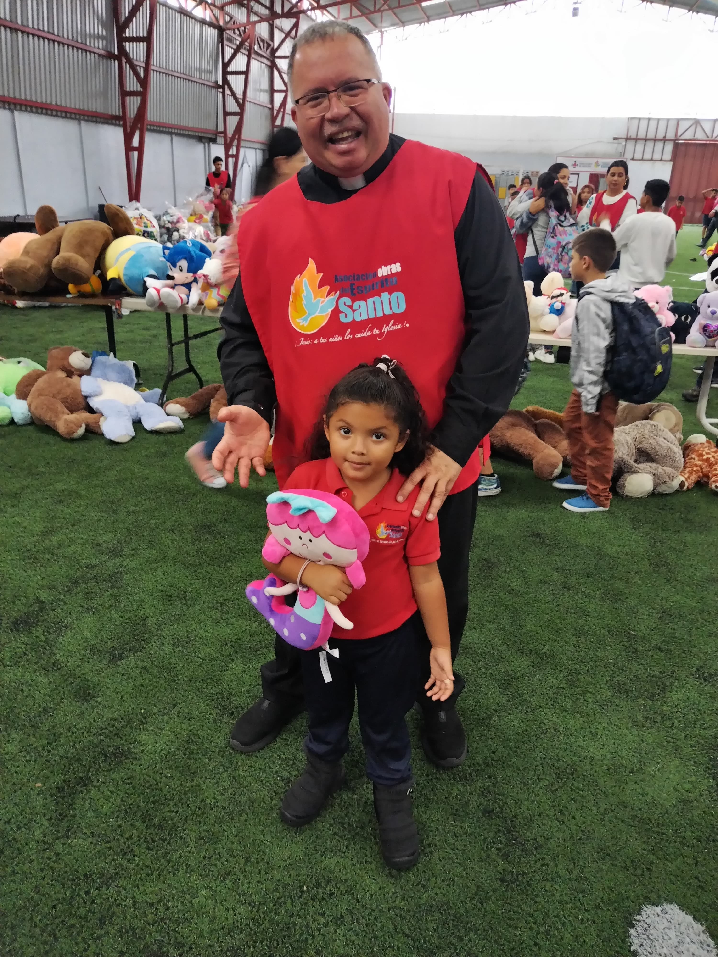 El padre Sergio Valverde de Obras del Espíritu Santo, comenzó el lunes 11 de noviembre a acomodar los peluches que los ticos donaron en la lluvia de peluches en el estadio Ricardo Saprissa. En la foto con la niña Nazil Orozco Corea de prekinder en Obras del Espíritu Santo.