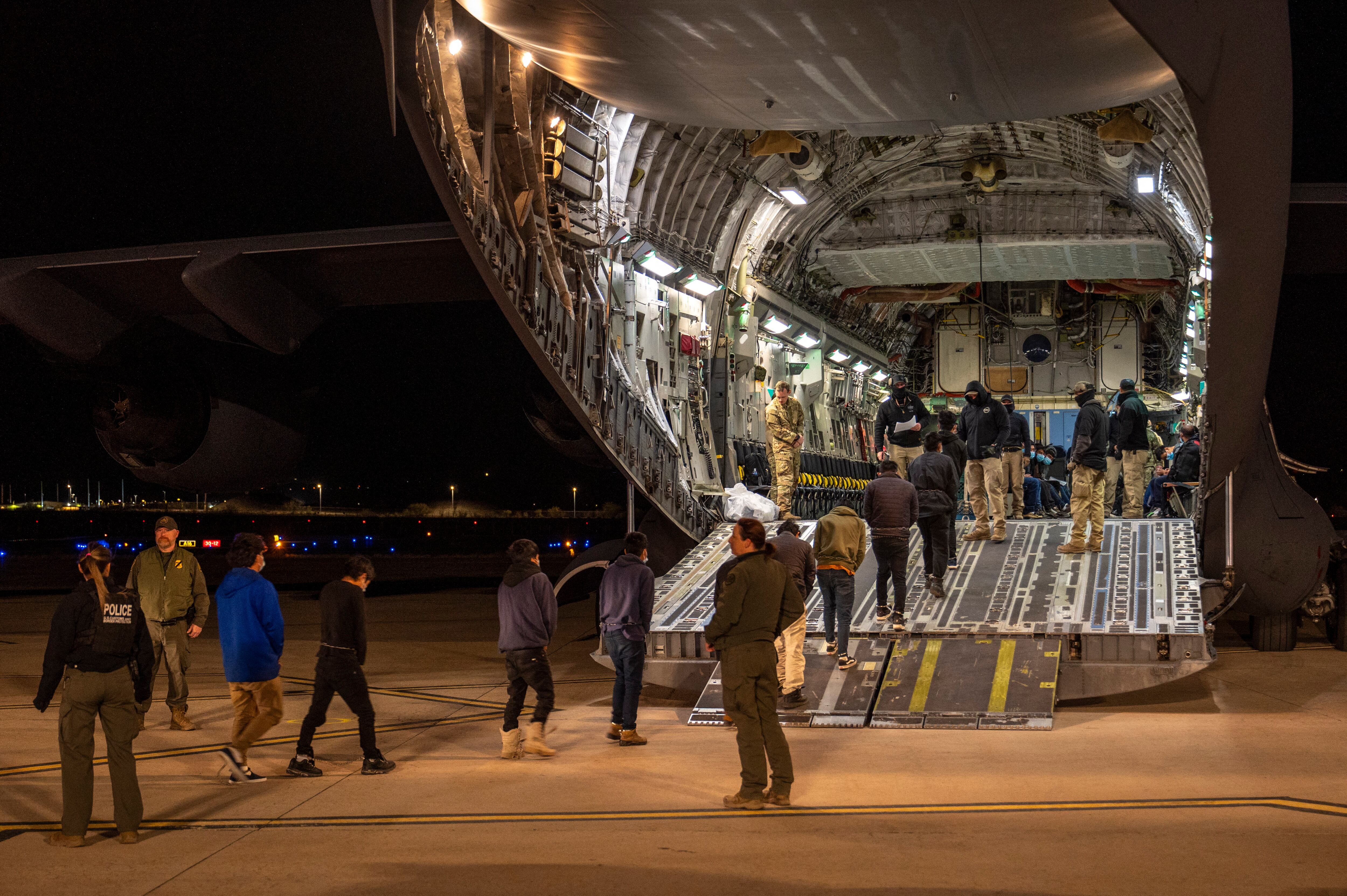 Esta imagen publicada por el Departamento de Defensa muestra a aviadores estadounidenses y agentes de Aduanas y Protección Fronteriza de Estados Unidos guiando a inmigrantes indocumentados hacia un C-17 Globemaster III en el Aeropuerto Internacional de Tucson, Arizona.