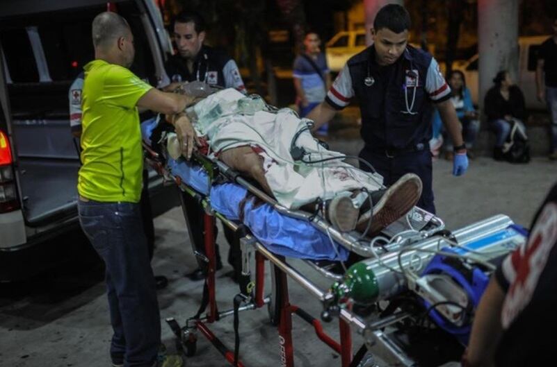 Kenneth Delgado Fernández recibió once balazos y vivió para contarla, en la foto, el 1 de abril del 2016, cuando lo montaban a la ambulancia y su papá lo consolaba.