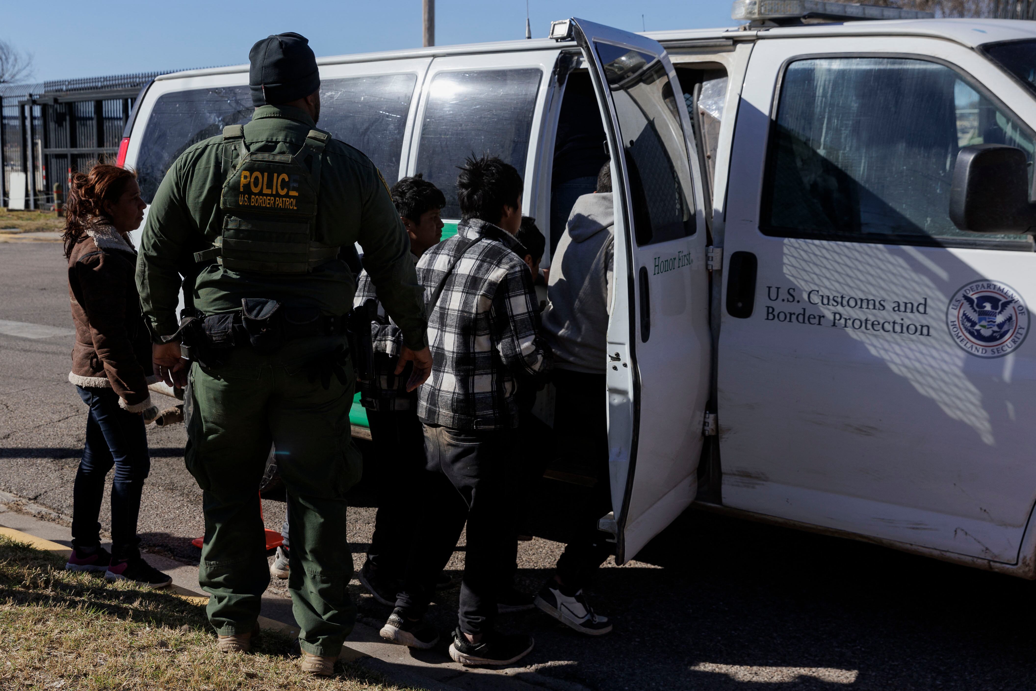 Un agente de la Patrulla Fronteriza guía a los migrantes que cruzaron a Shelby Park hacia una camioneta de la Patrulla Fronteriza para ser llevados a un centro de procesamiento en Eagle Pass, Texas.