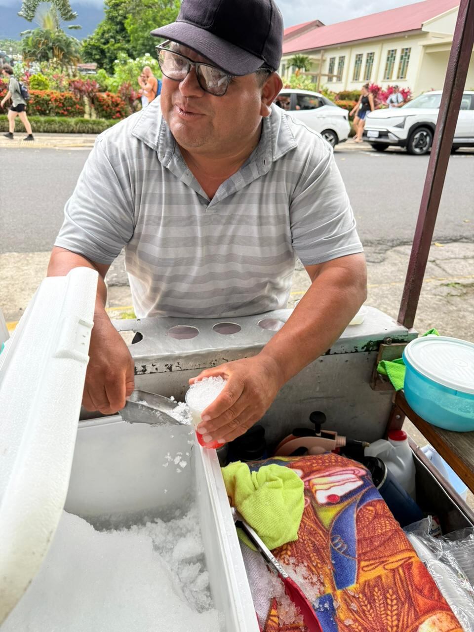 Las personas buscan dónde esconderse cuando cae un aguacero en La Fortuna de San Carlos, pero el nicaragüense, Antonio Padilla Madriz, más bien sonríe y le agradece a Dios porque así venderá más copos