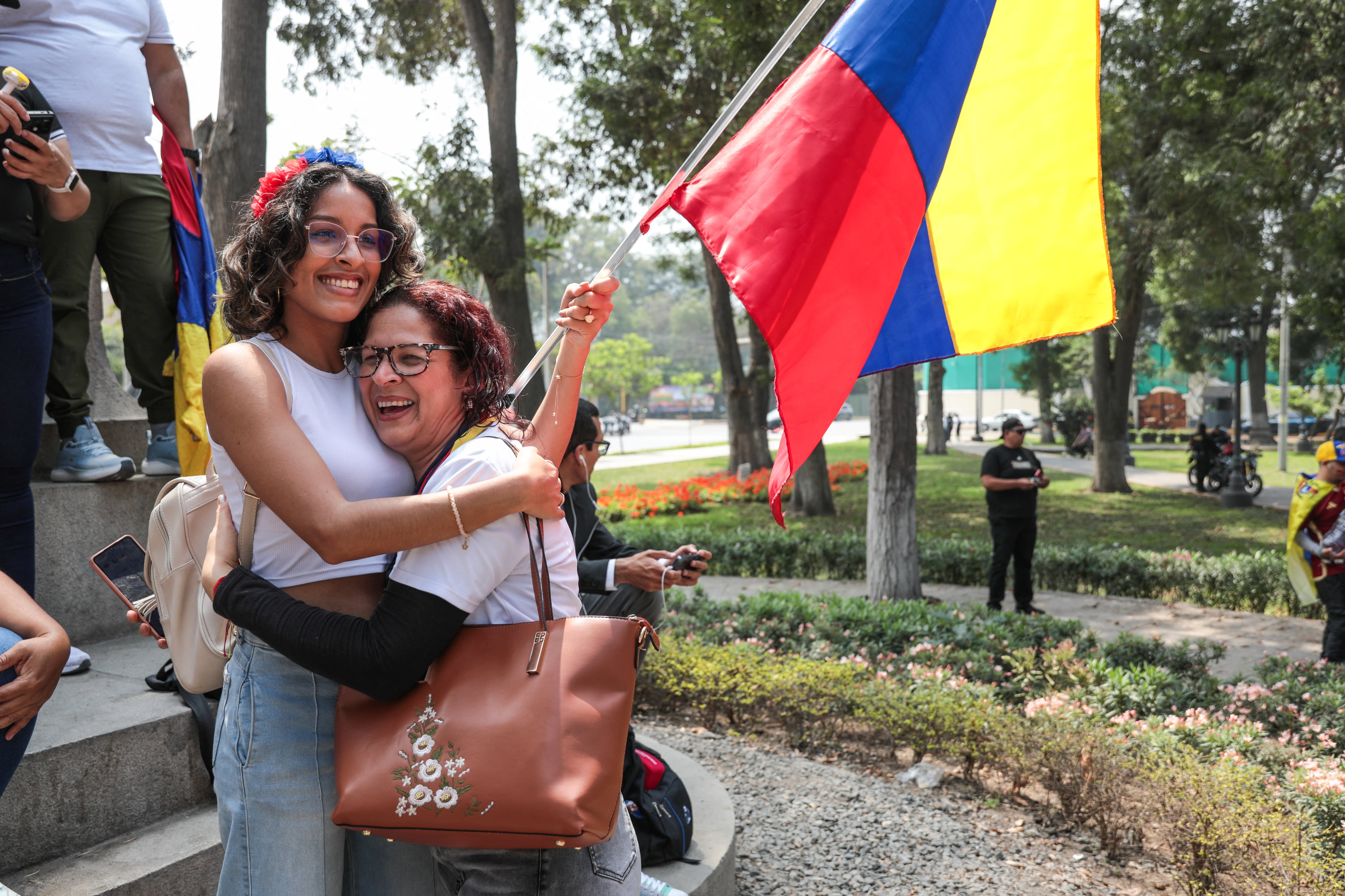 Venezuelans living in Peru celebrate with a national flag at the Miguel de Cervantes park, near the Venezuelan Embassy in Lima on January 3, 2026, after US forces captured Venezuelan leader Nicolas Maduro. President Donald Trump said Saturday that US forces had captured Venezuela's leader Nicolas Maduro after bombing the capital Caracas and other cities in a dramatic climax to a months-long standoff between Trump and his Venezuelan arch-foe. (Photo by Connie FRANCE / AFP)