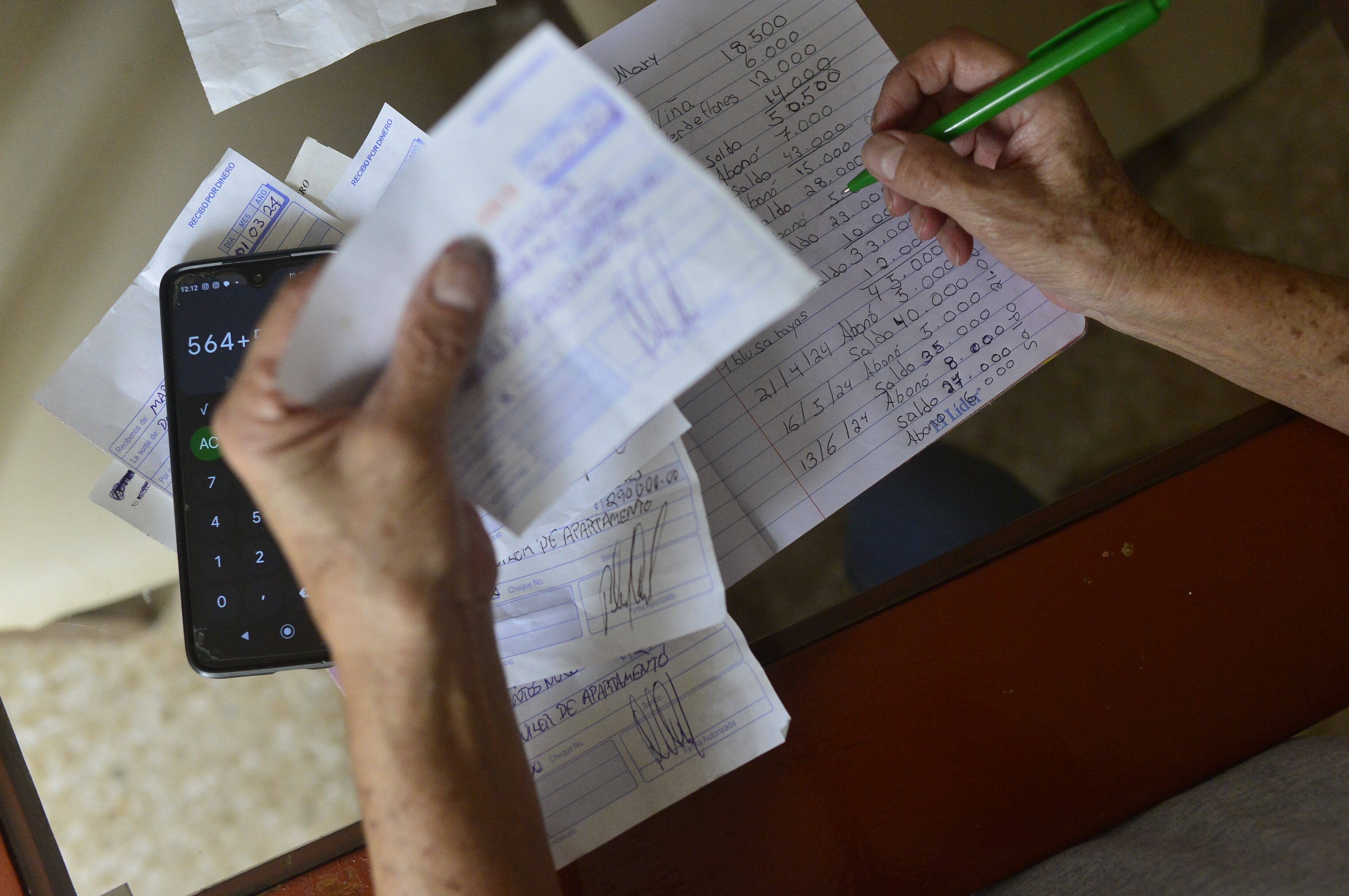 Mano de una persona mayor haciendo cuentas con una calculadora en un escritorio.