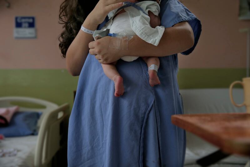 Una mujer a la que no se le ve el rostro carga a un bebé recién nacido
