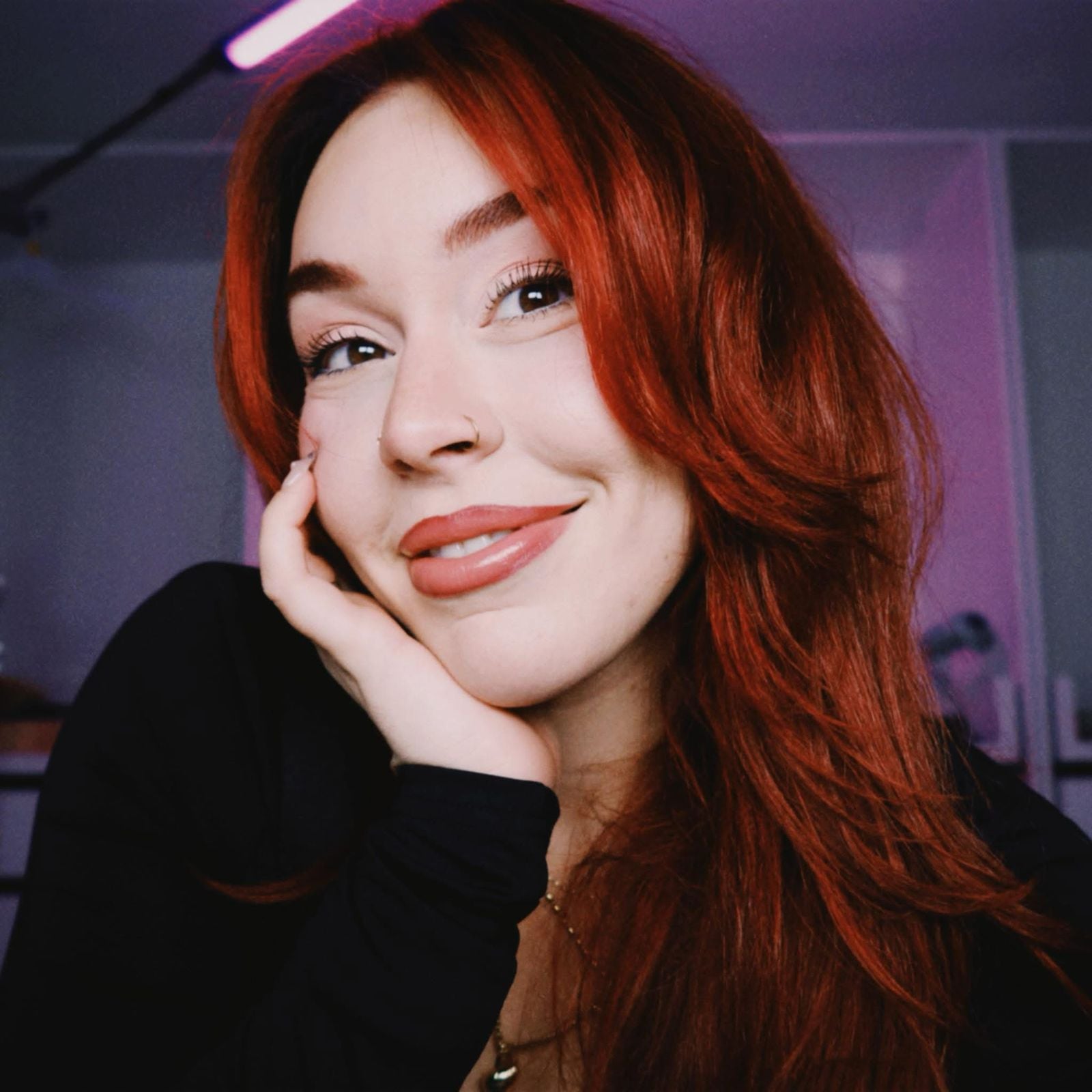 एक हसणारी स्त्री तिचे डोके बाजूला झुकवते आणि तिचा हात तिच्या हनुवटीवर