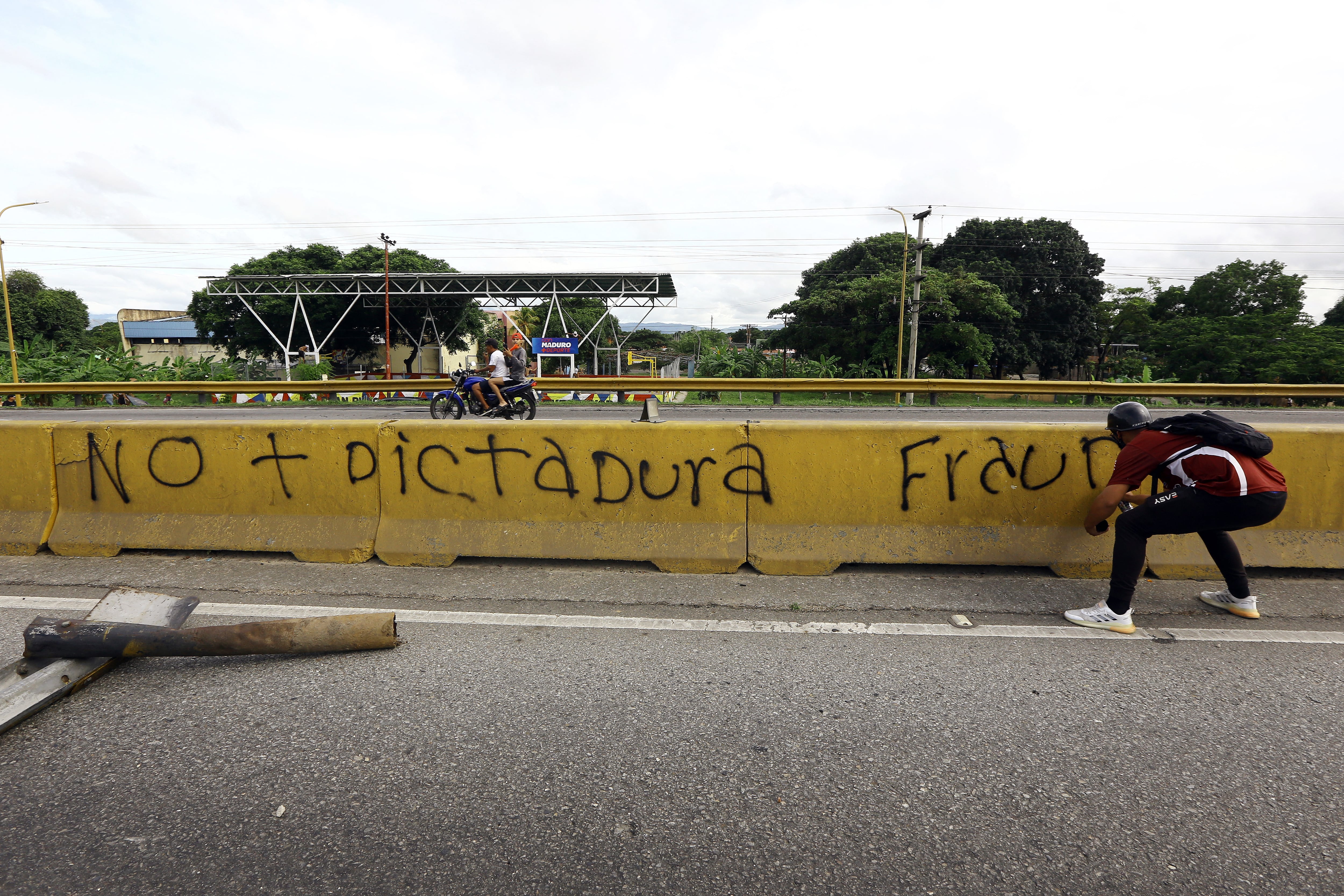 Un hombre escribe "no más dictadura, fraude" en una pared durante una protesta contra el gobierno de Nicolás Maduro en Valencia, estado Carabobo, Venezuela. (Foto: AFP)