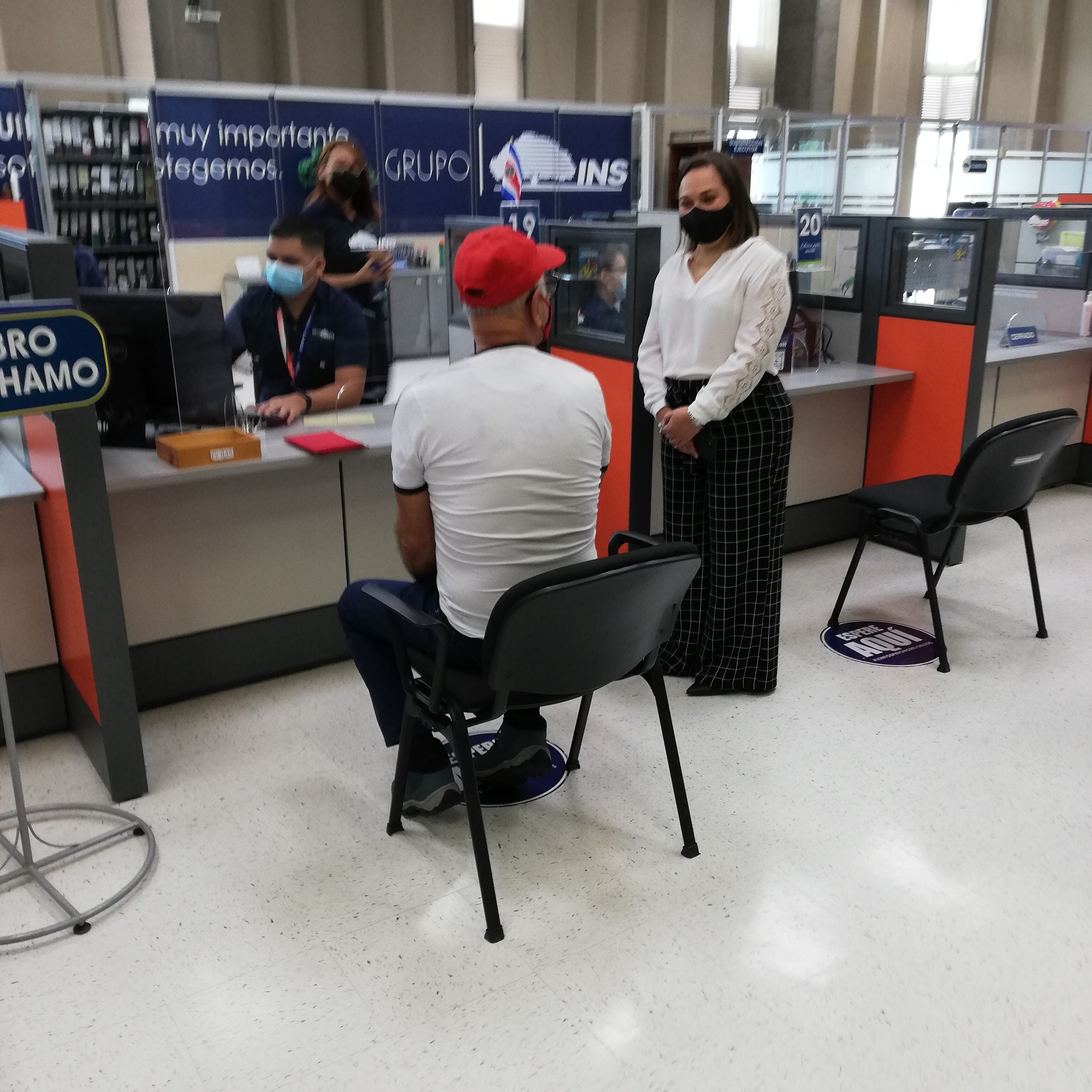Don Carlos Chacón Alvarado, pensionado y de 73 años, cumplió por 13 años consecutivos su compromiso de ser el primer tico que paga el derecho de circulación 2022.En la foto, don Pablo Abarca del INS le verifica los datos a don Carlos cuando él conversa con doña Raquel Cascante Ardón, jefe de la sede central del INS.
