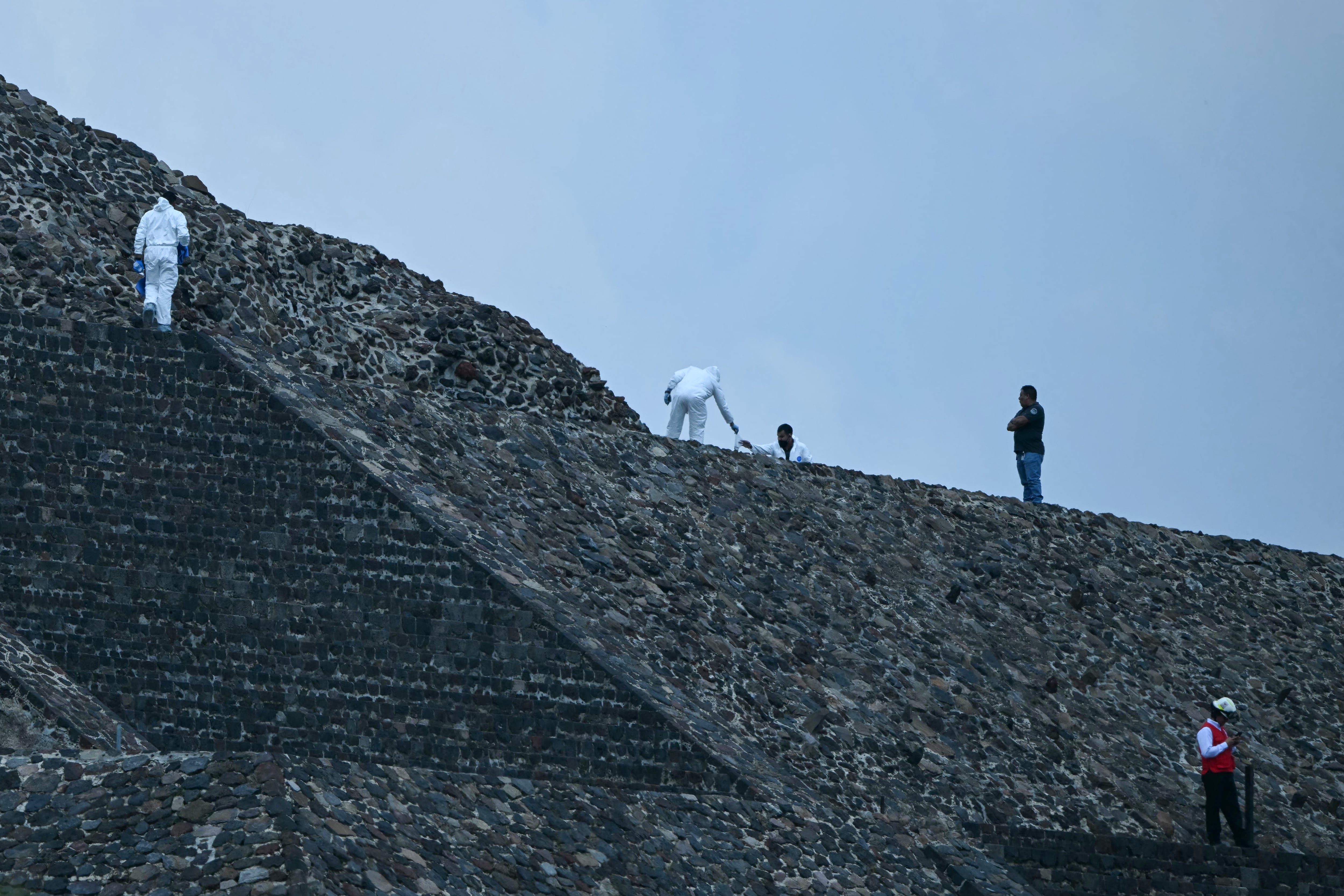 Forensic experts and members of the Red Cross work on the Pyramid of the Moon at the Teotihuacan archaeological zone following a shooting in Teotihuacan, State of Mexico, on April 20, 2026. A Canadian woman was shot dead on April 20 at the Teotihuacan pyramids archaeological zone in central Mexico by a man who later killed himself, authorities said. (Photo by YURI CORTEZ / AFP)