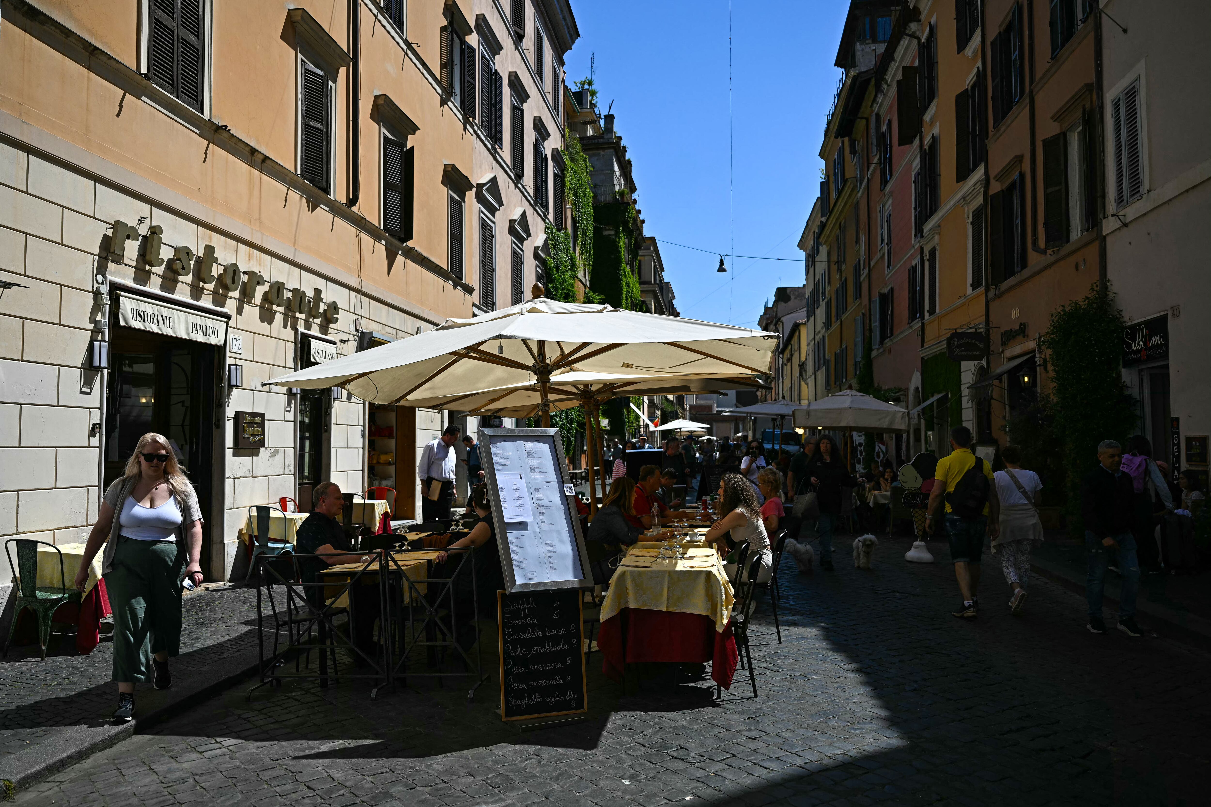 Clientes se sientan en la terraza de un restaurante en la calle Borgo Pio, en Roma, a la espera del cónclave 2025.