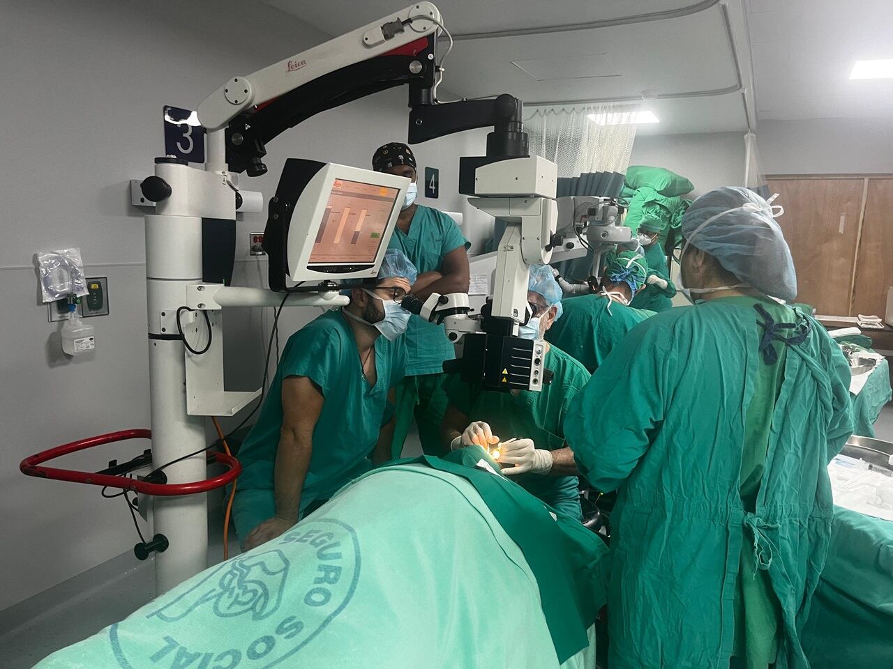 Quirófano con personal vestido de verde operando una persona.